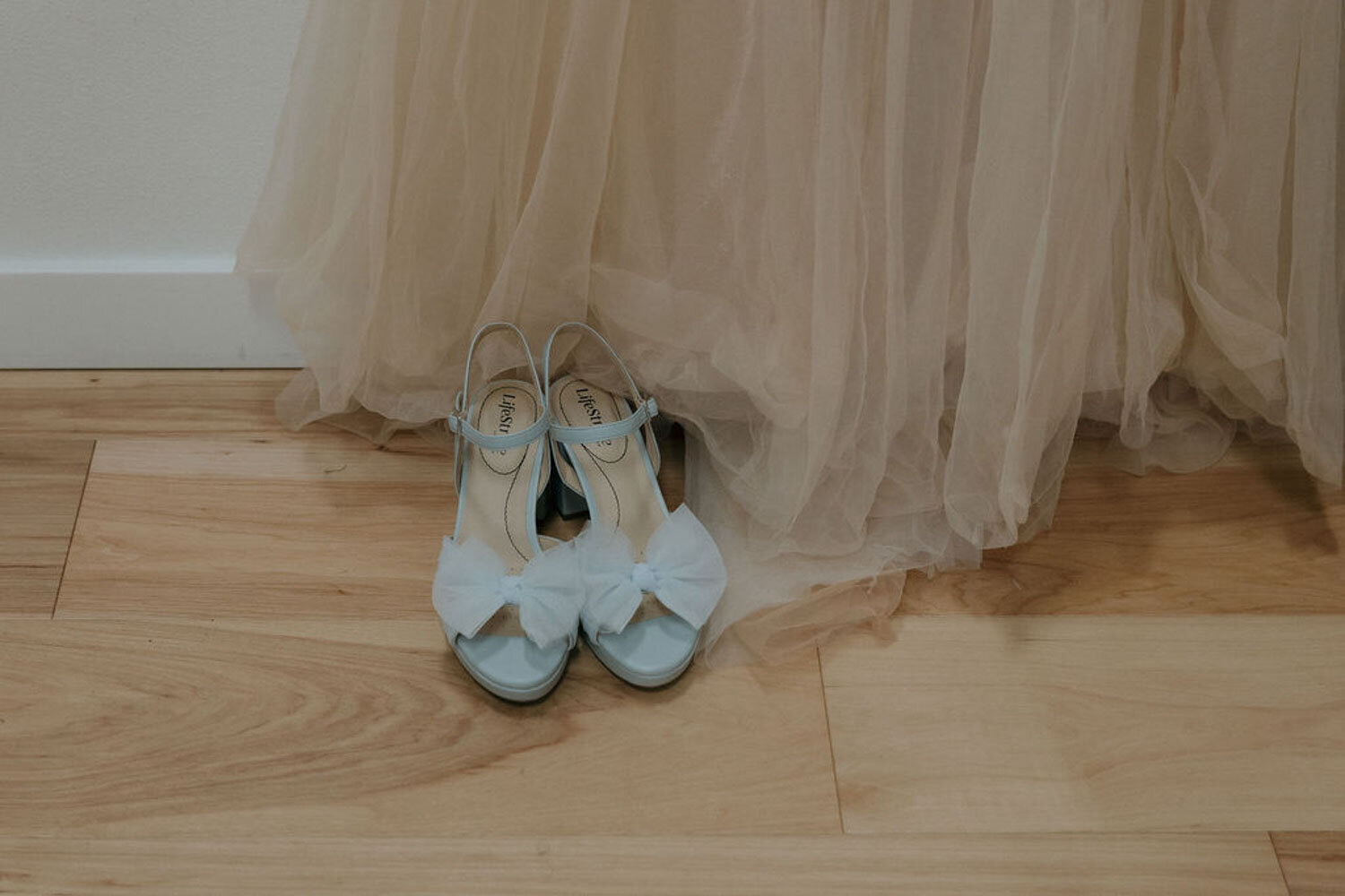 Close-up of bride’s blue wedding shoes beside her gown