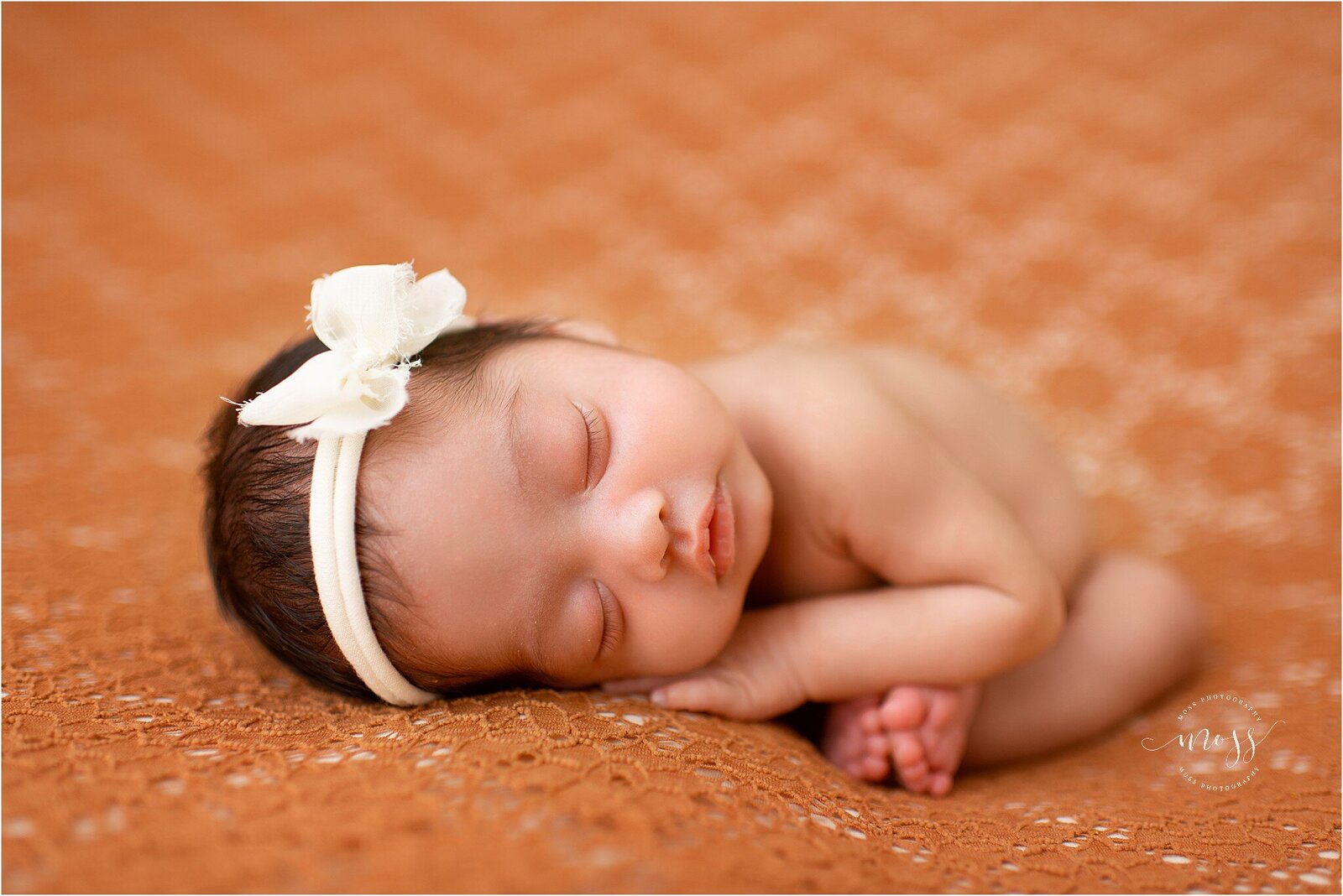 newborn on orange lace blanket