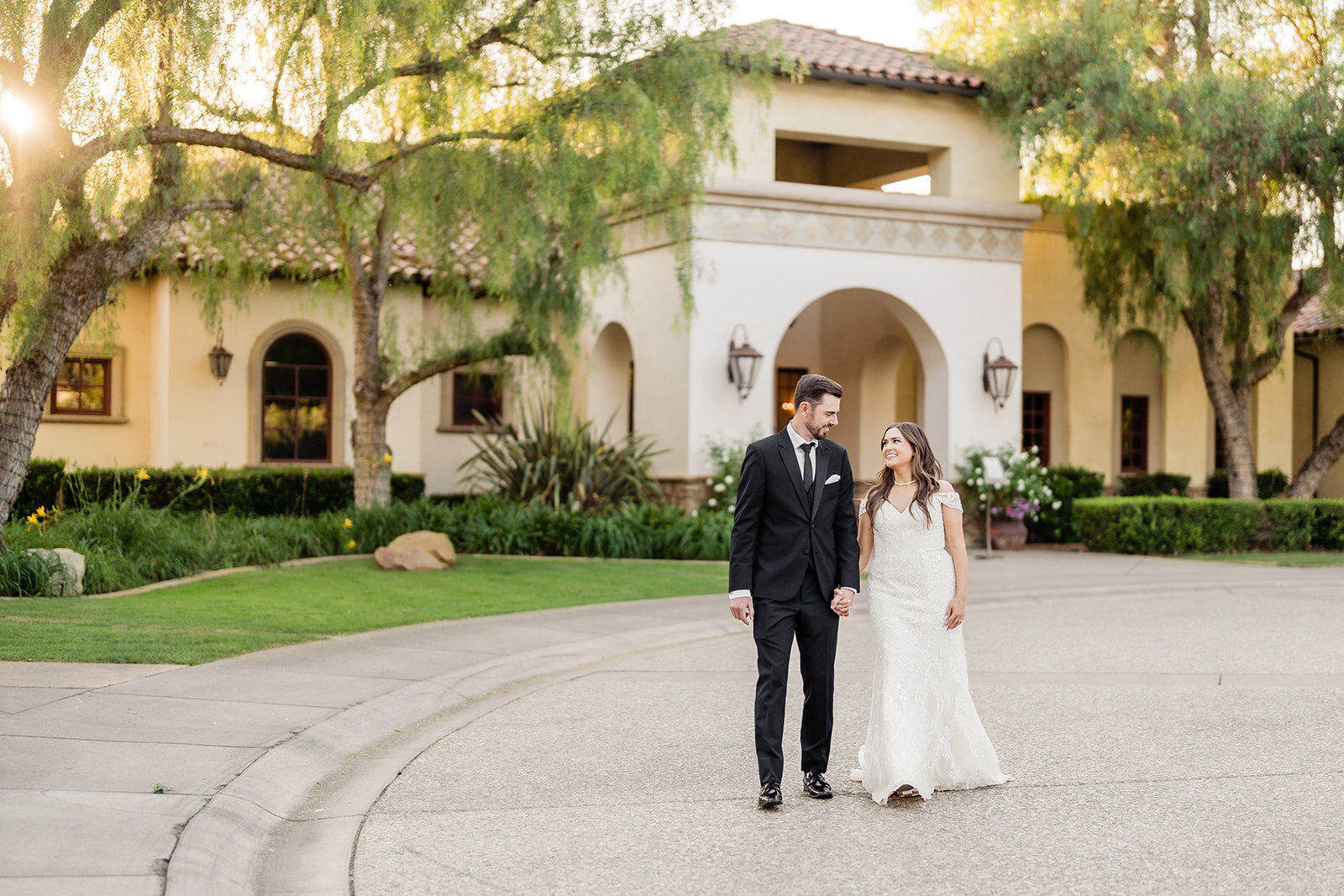 A bride and groom walking hand in hand in front of their venue at Maderas Golf Club
