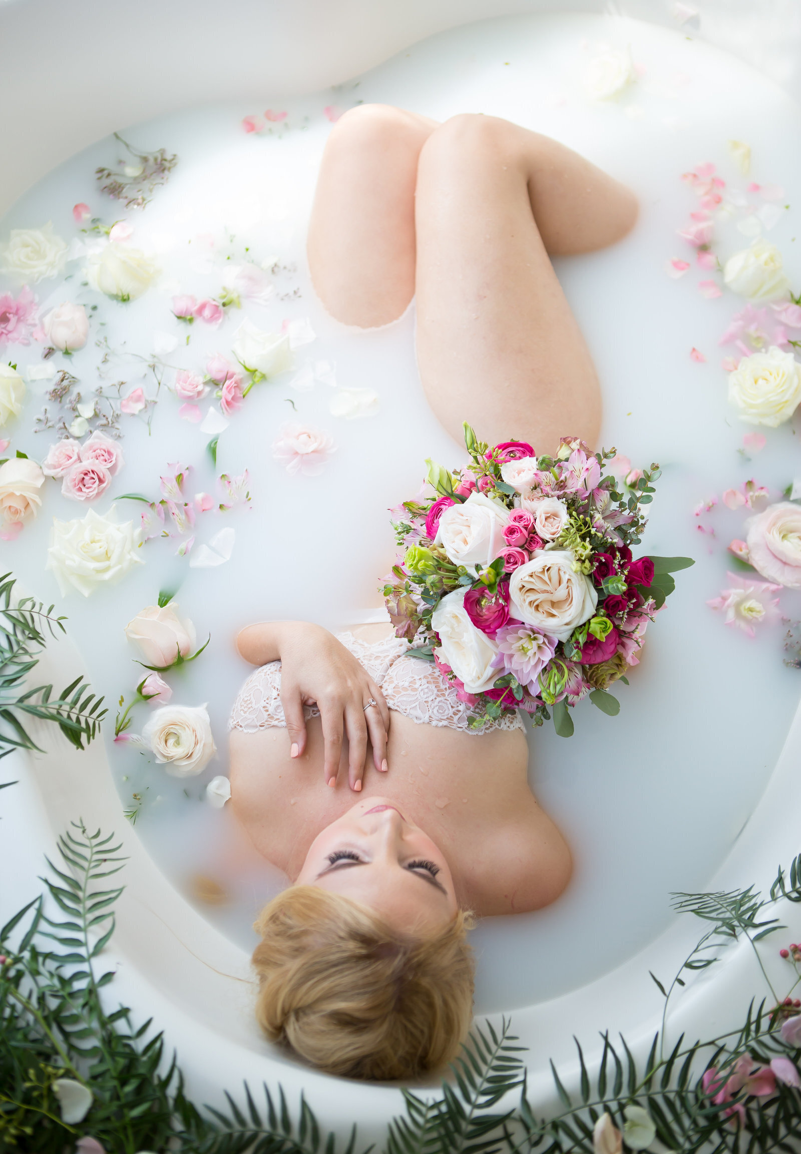 Woman sitting in milk bath surrounded by florals