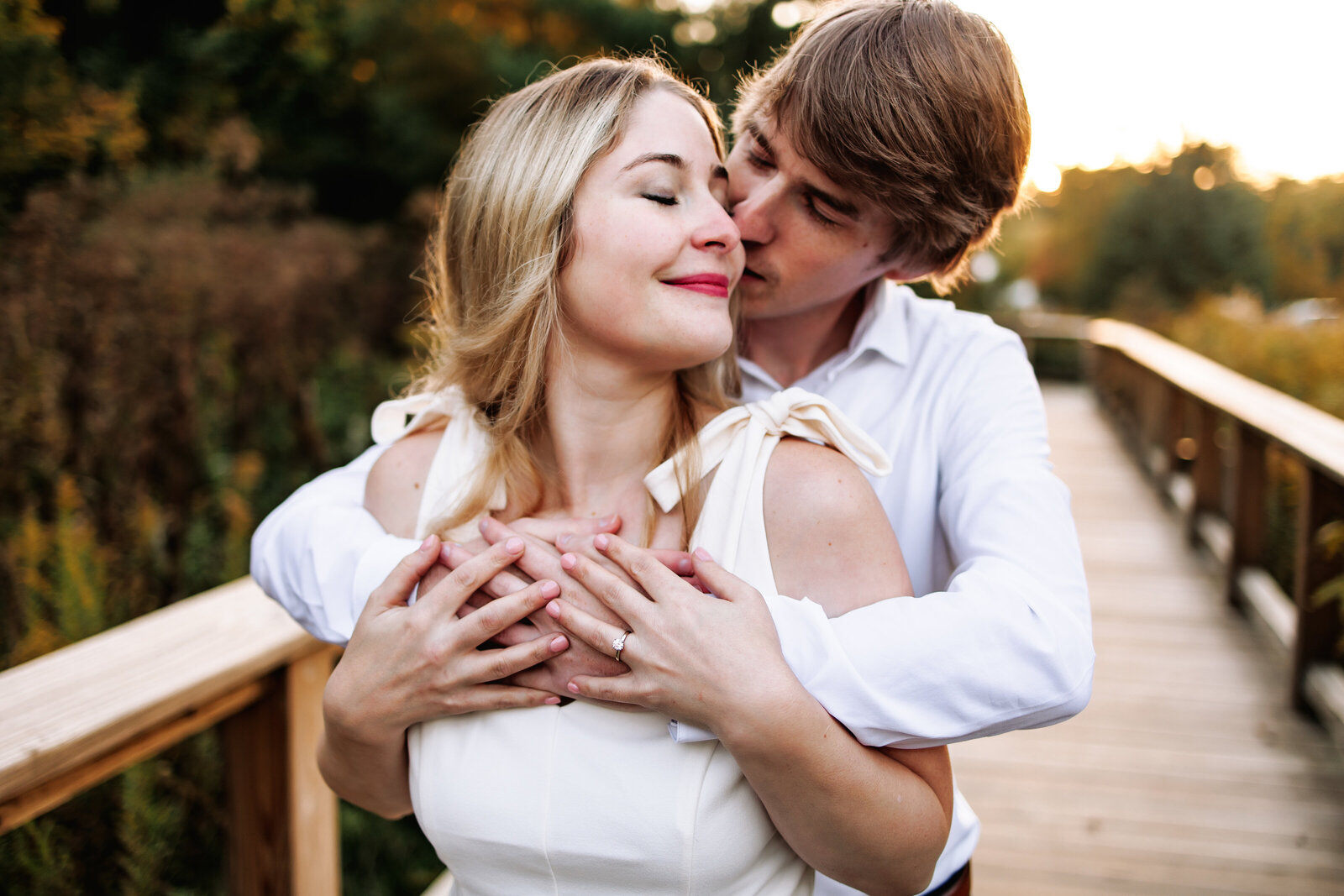 Man intimately embraces is fiancé from behind and kisses her cheek