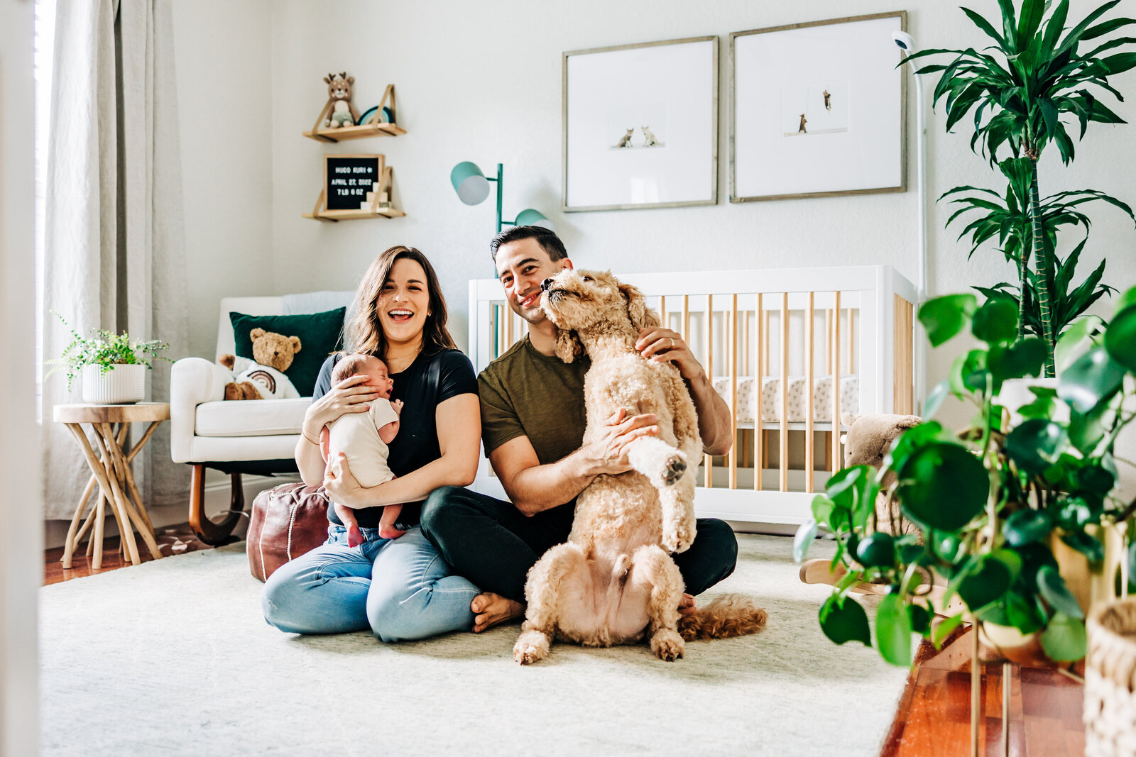 st pete family photo of a newborn with thier dog laughing in a well lit nursery