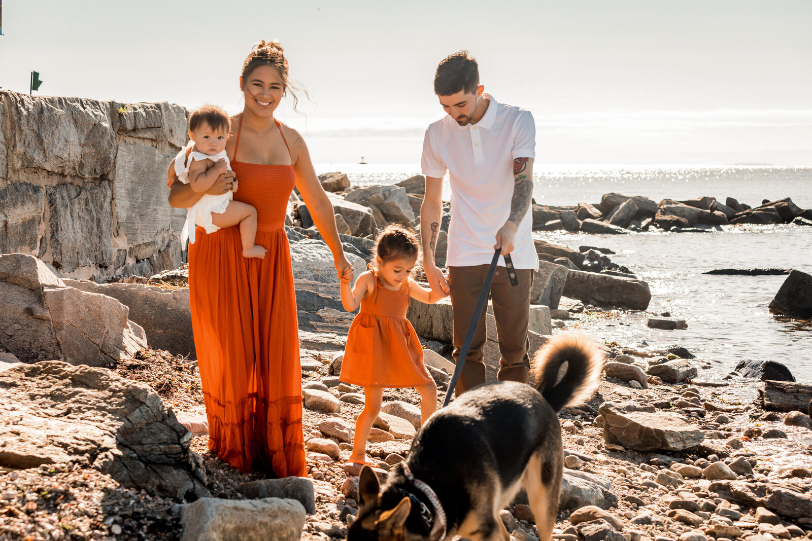 family smiling and walking with their dog on the beach