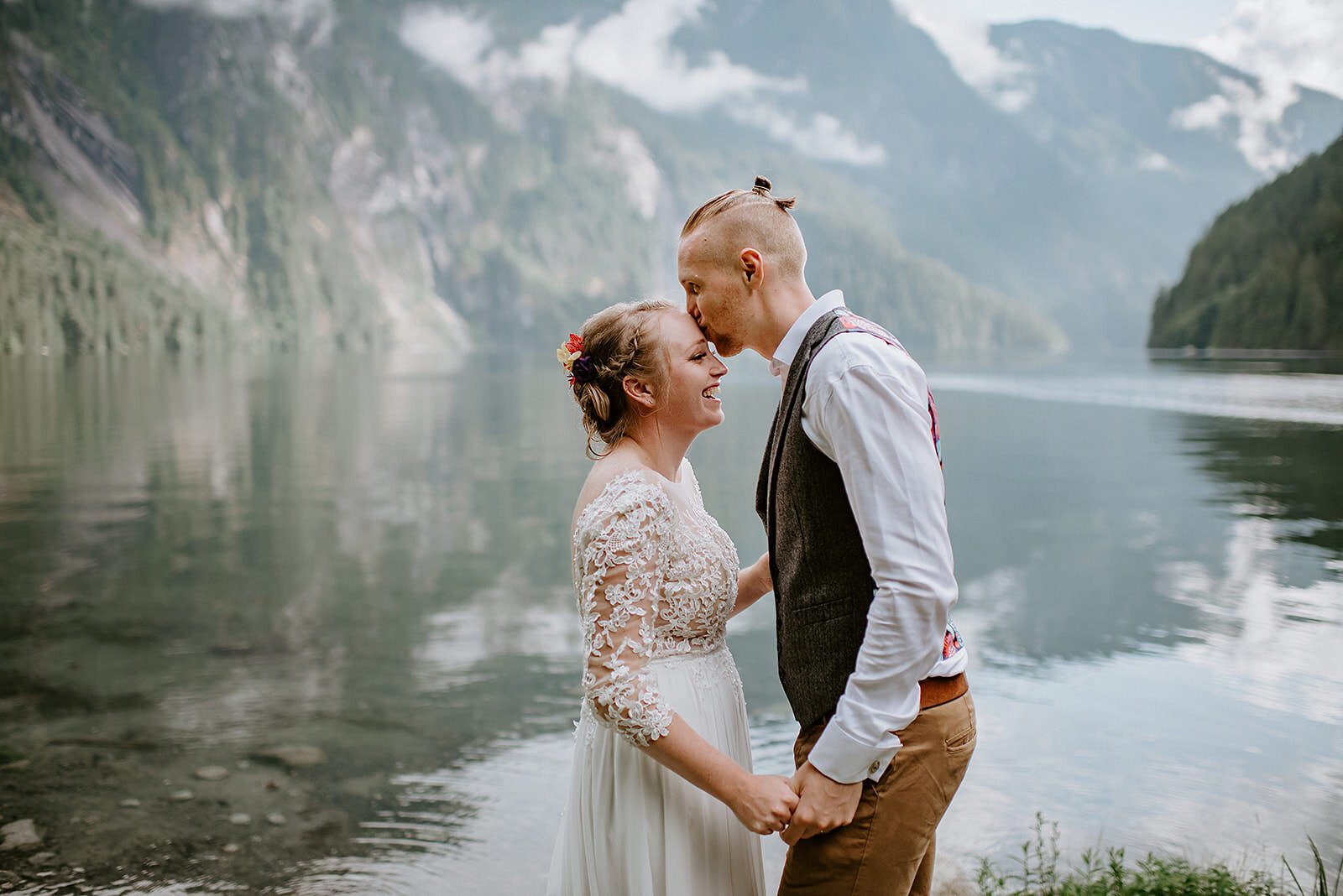Couple standing against a coastal mountain backdrop during their romantic adventure elopement.