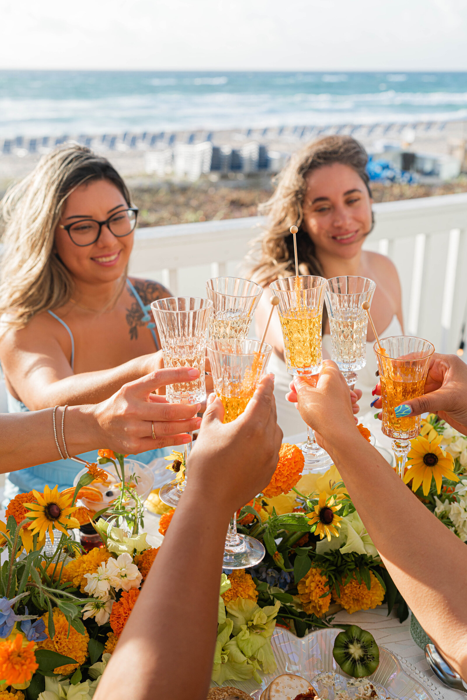 girls at brunch with orange and blue flowers toasting champagne