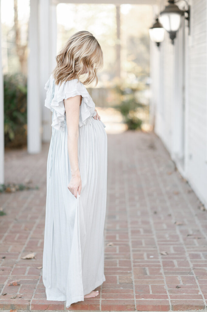 Pregnant woman walks on a brick porch by Nashville maternity photographer Kristie Lloyd