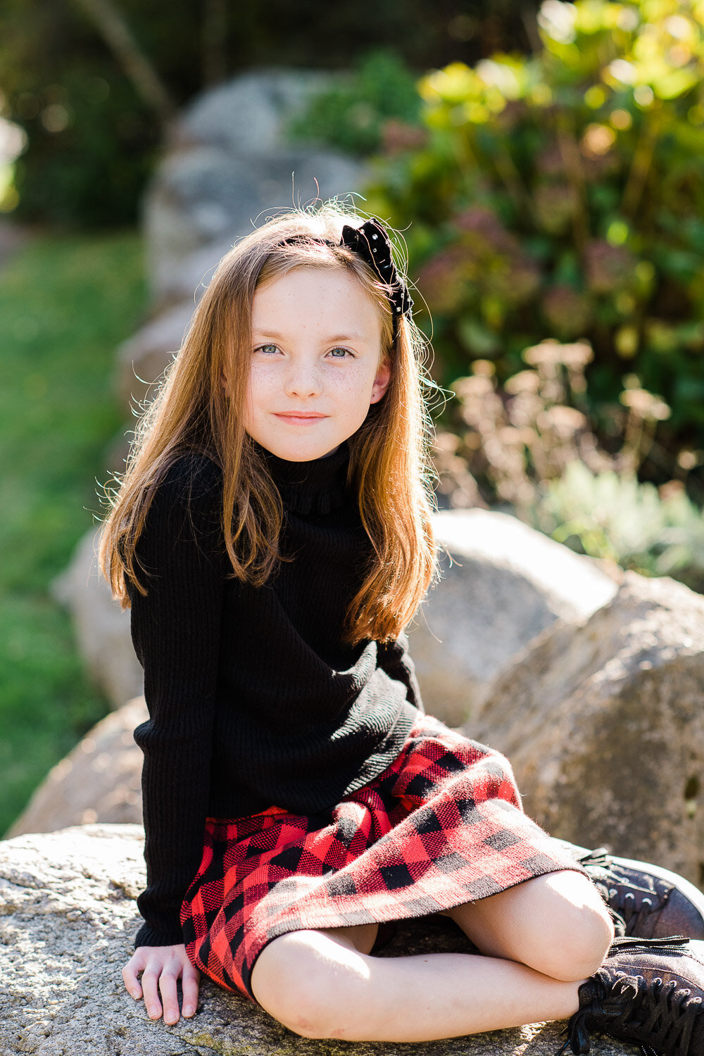 young girl sitting on rock in sunlight