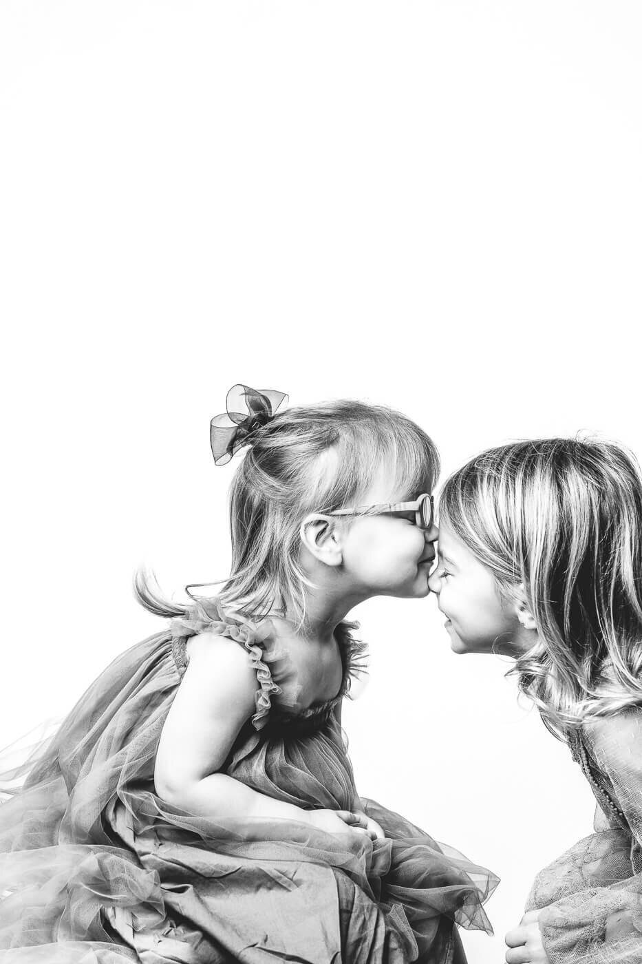 Younger sister lightly kissing her older sister on the nose