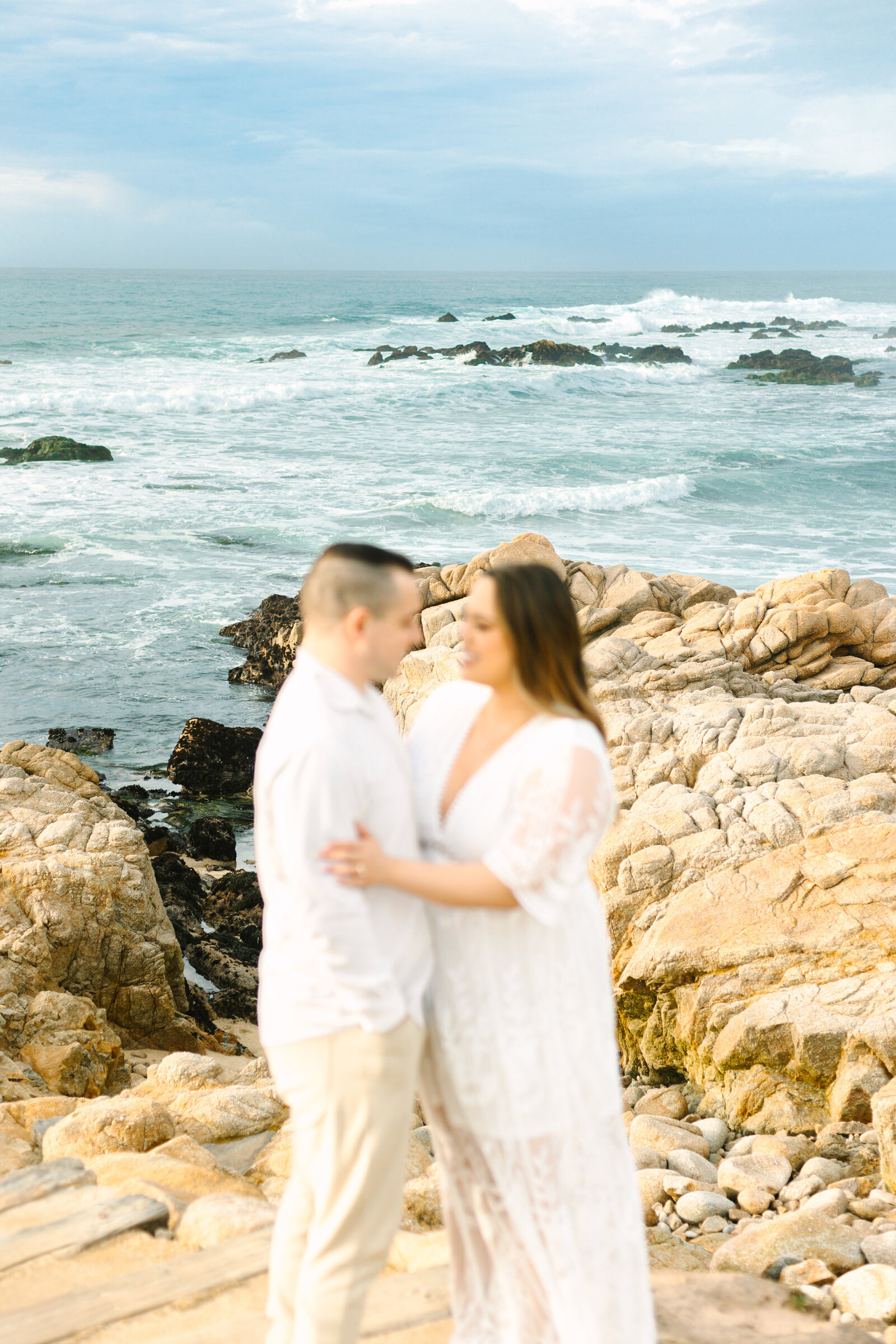 An engaged man and woman take photos on the beach in Pacific Grove, Monterey, California near Big Sur.