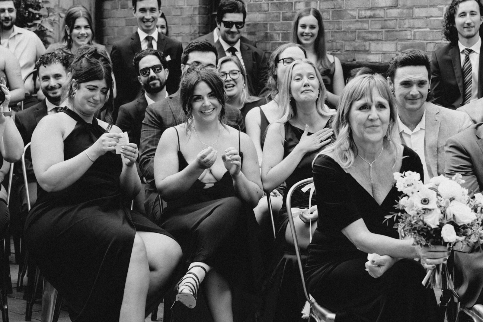 Happy and emotional reaction of the bride and groom's families and friends during the wedding ceremony, in black and white