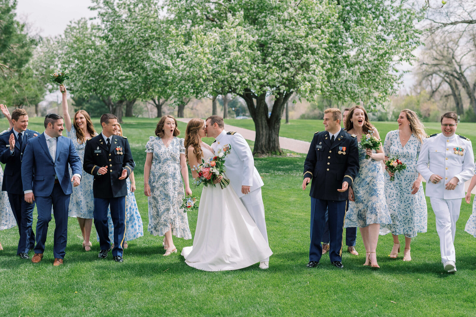 Bridal party walks and cheers as the bride and groom passionately kiss