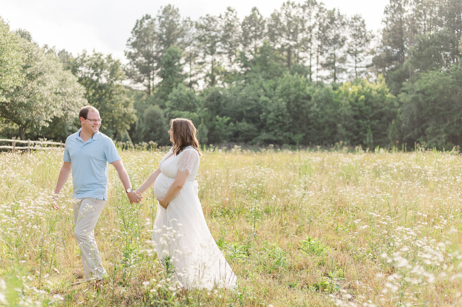Pregnant couple walking in a grassy field