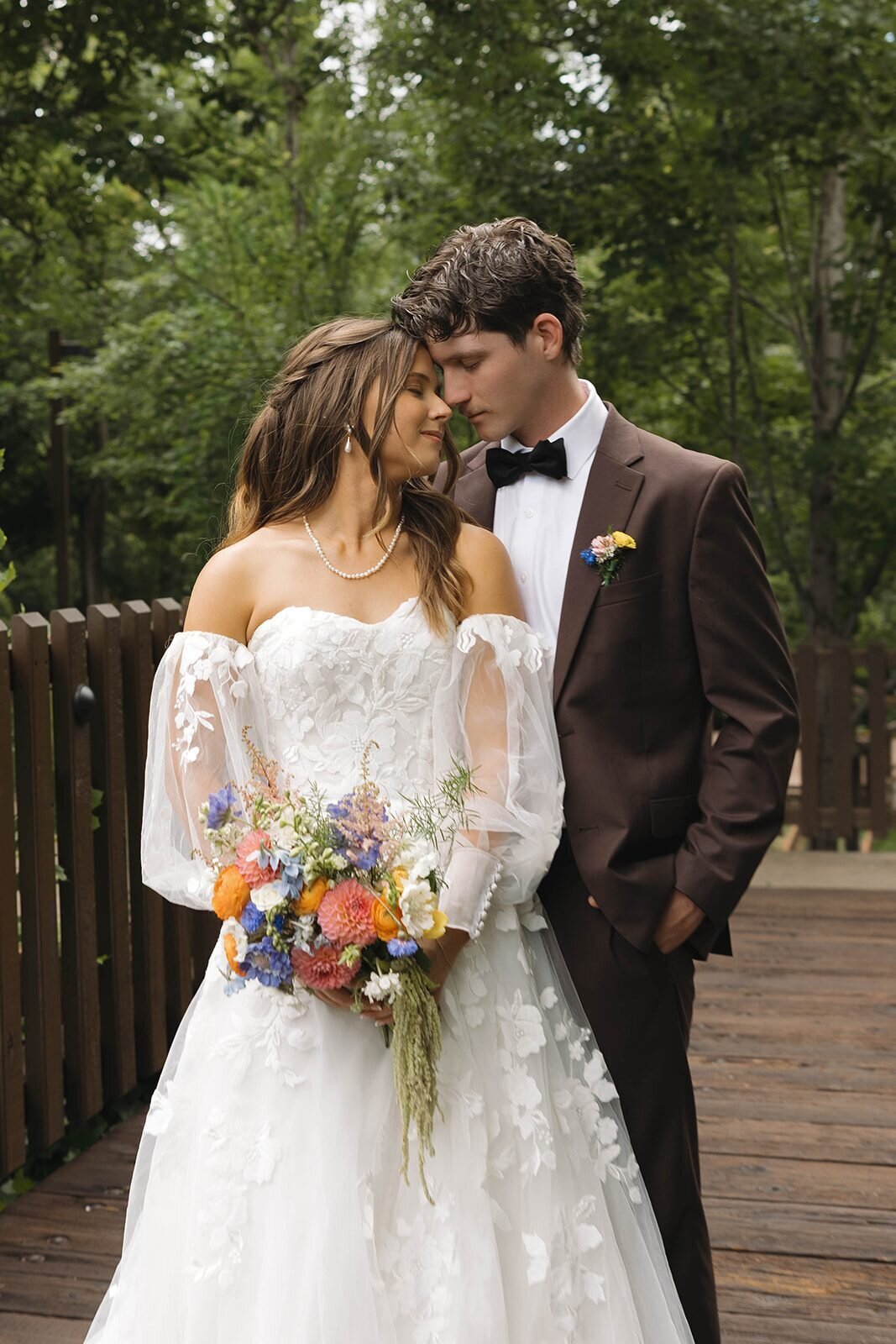 Emily and Bryce touching foreheads on a wooden bridge on their wedding day in Oregon