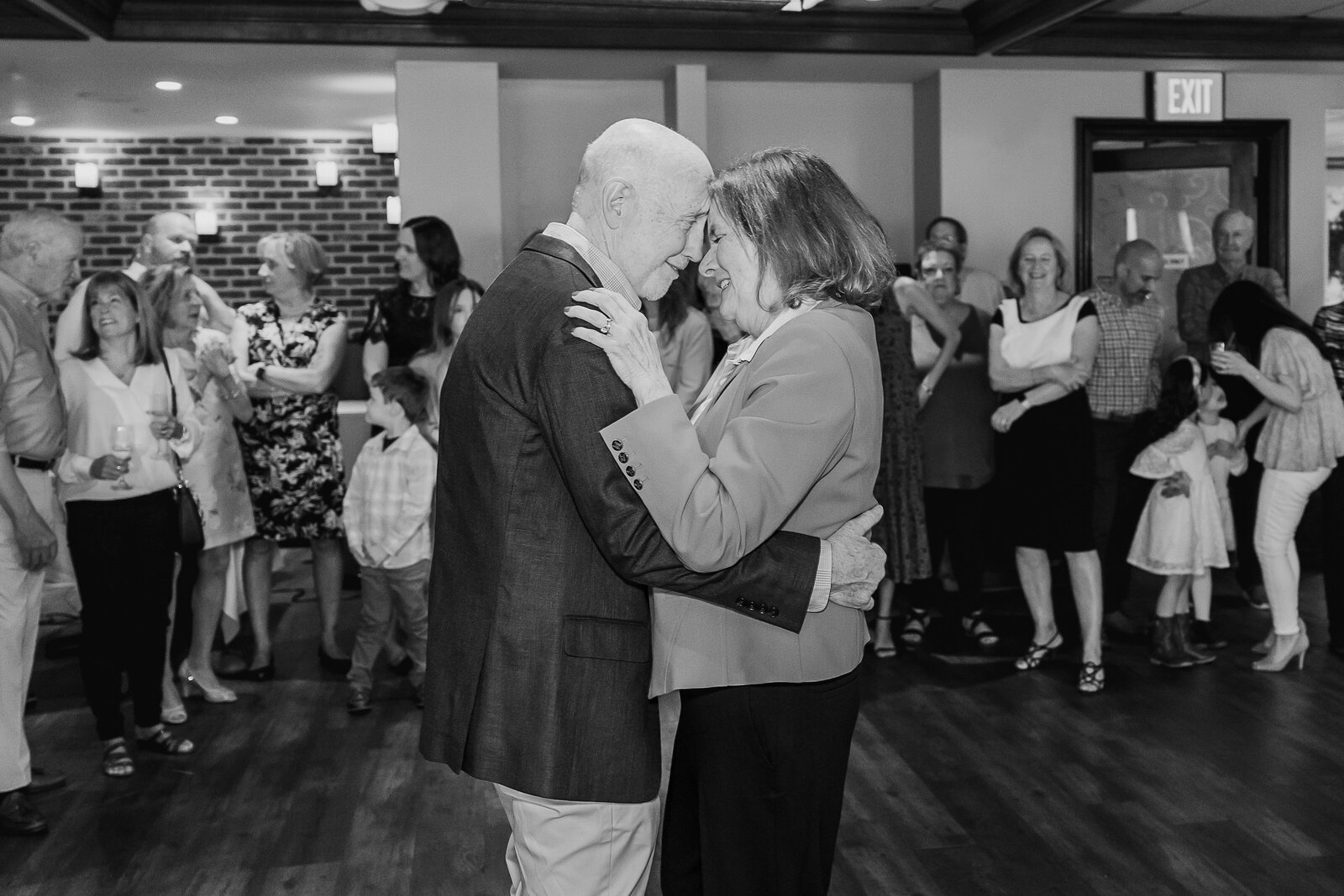 Couple dances, foreheads touching, at their anniversary party.