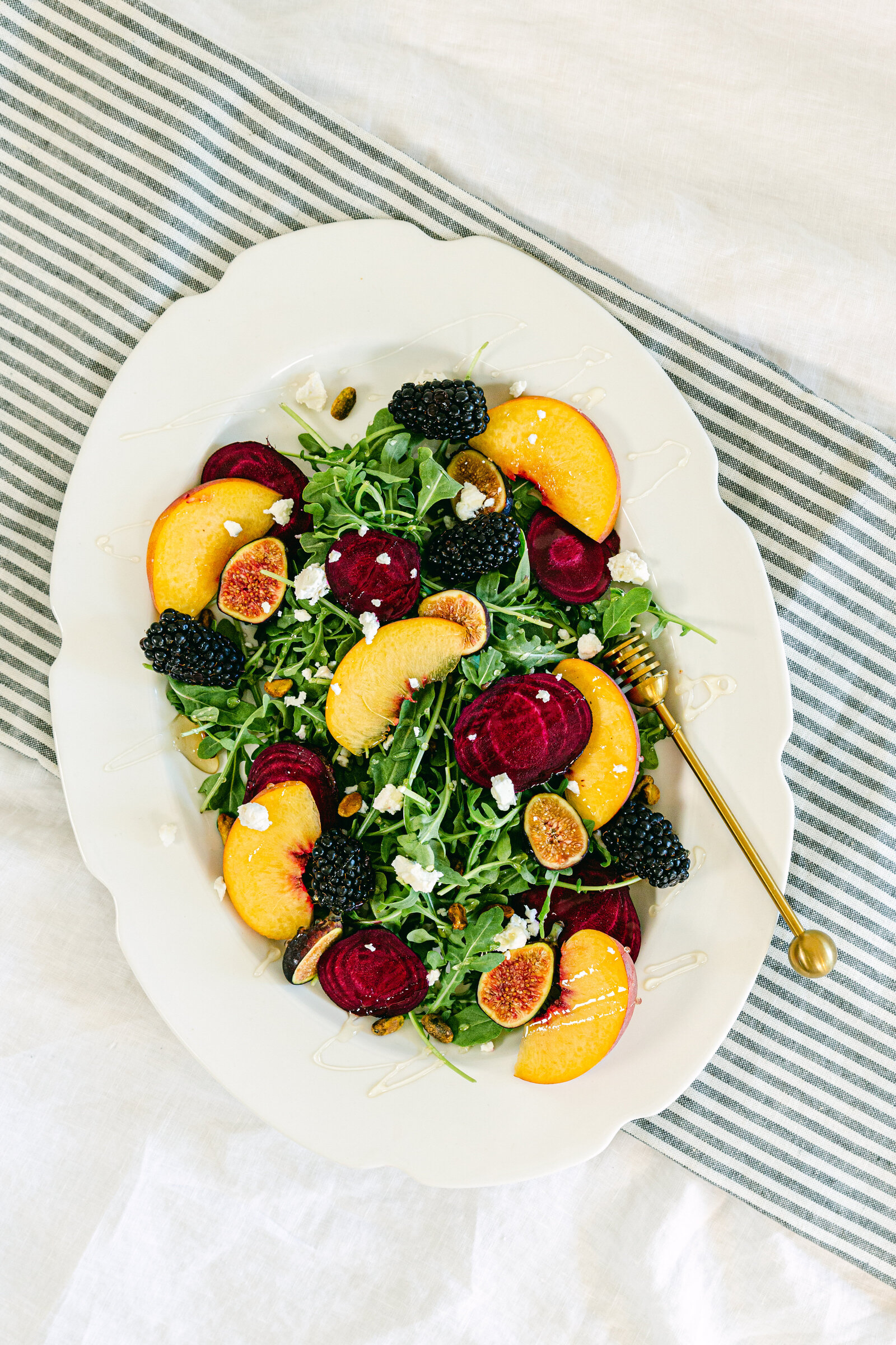 Colorful fall salad by food photographer Chelsea Loren with goat cheese, beets, nectarines, blackberries on white and striped backdrop for lifestyle food photography