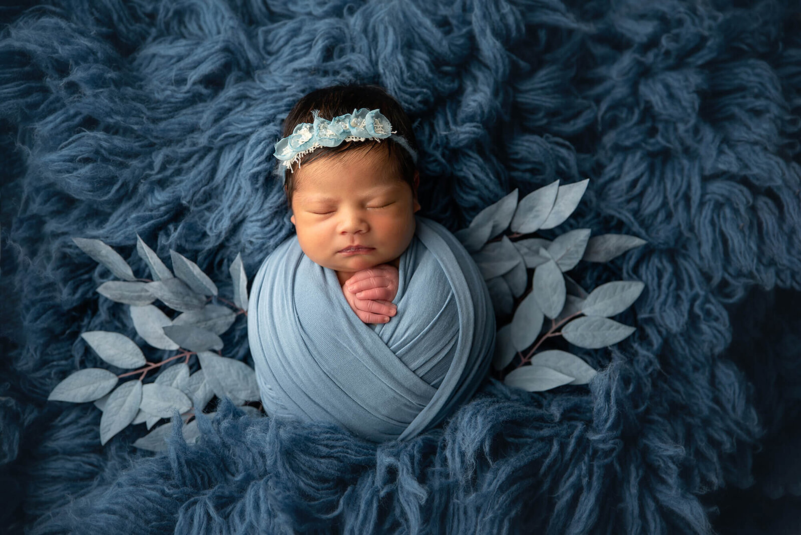 newborn wrapped in blue fabric