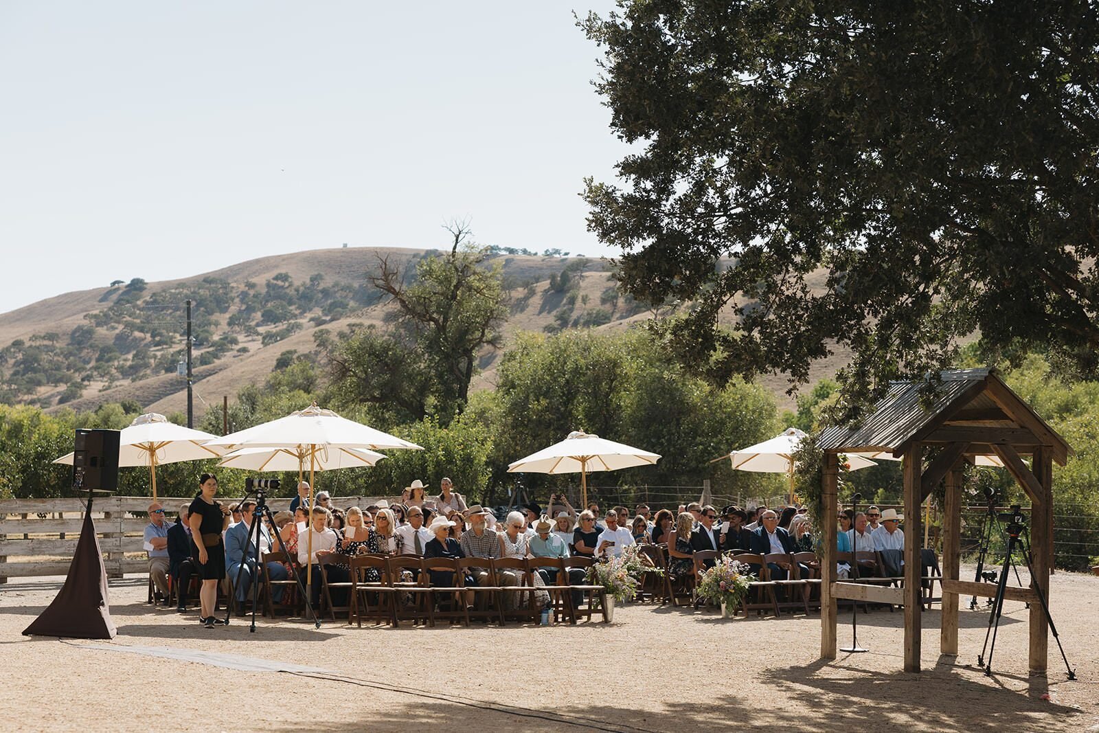 Outdoor ranch ceremony in San Miguel with white umbrellas and rolling hills