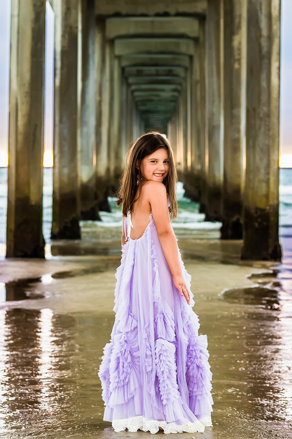 young girl posing under a pier in La Jolla