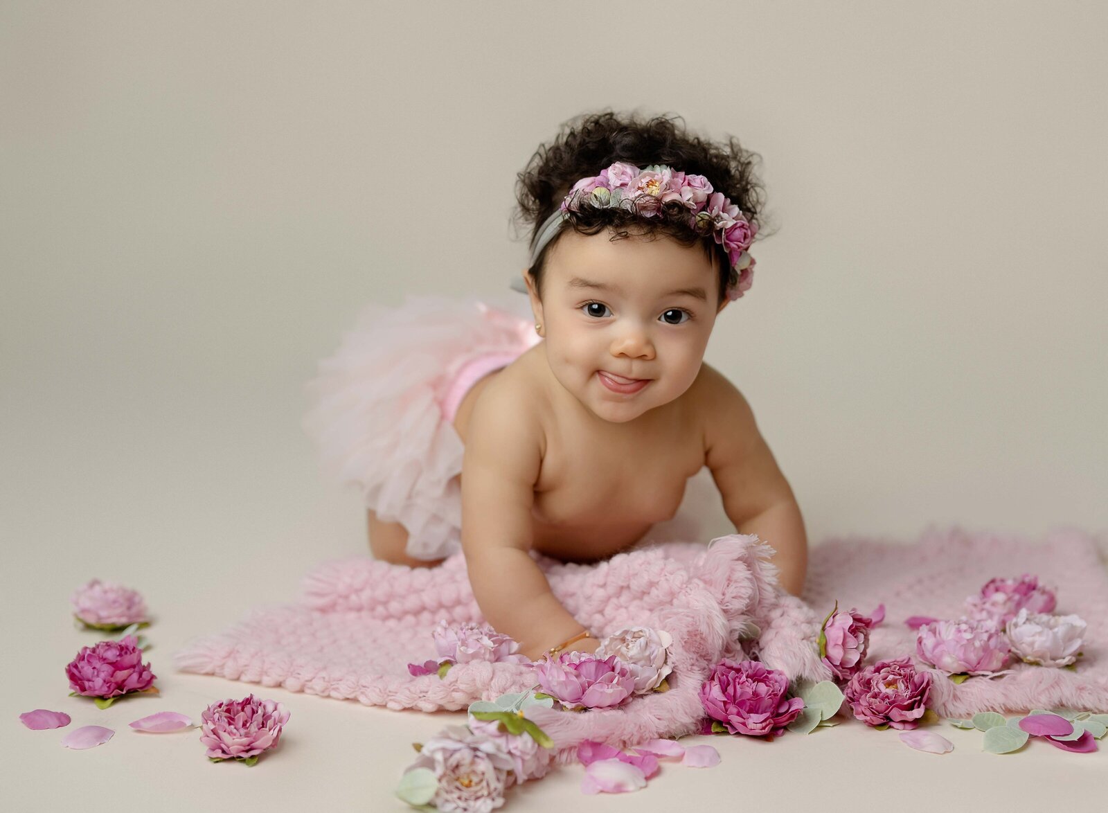 Milestone photos of baby girl crawling with pink flowers on floor. Baby milestone photo taken by Jenni Nikki Photography in Atlanta, GA. 