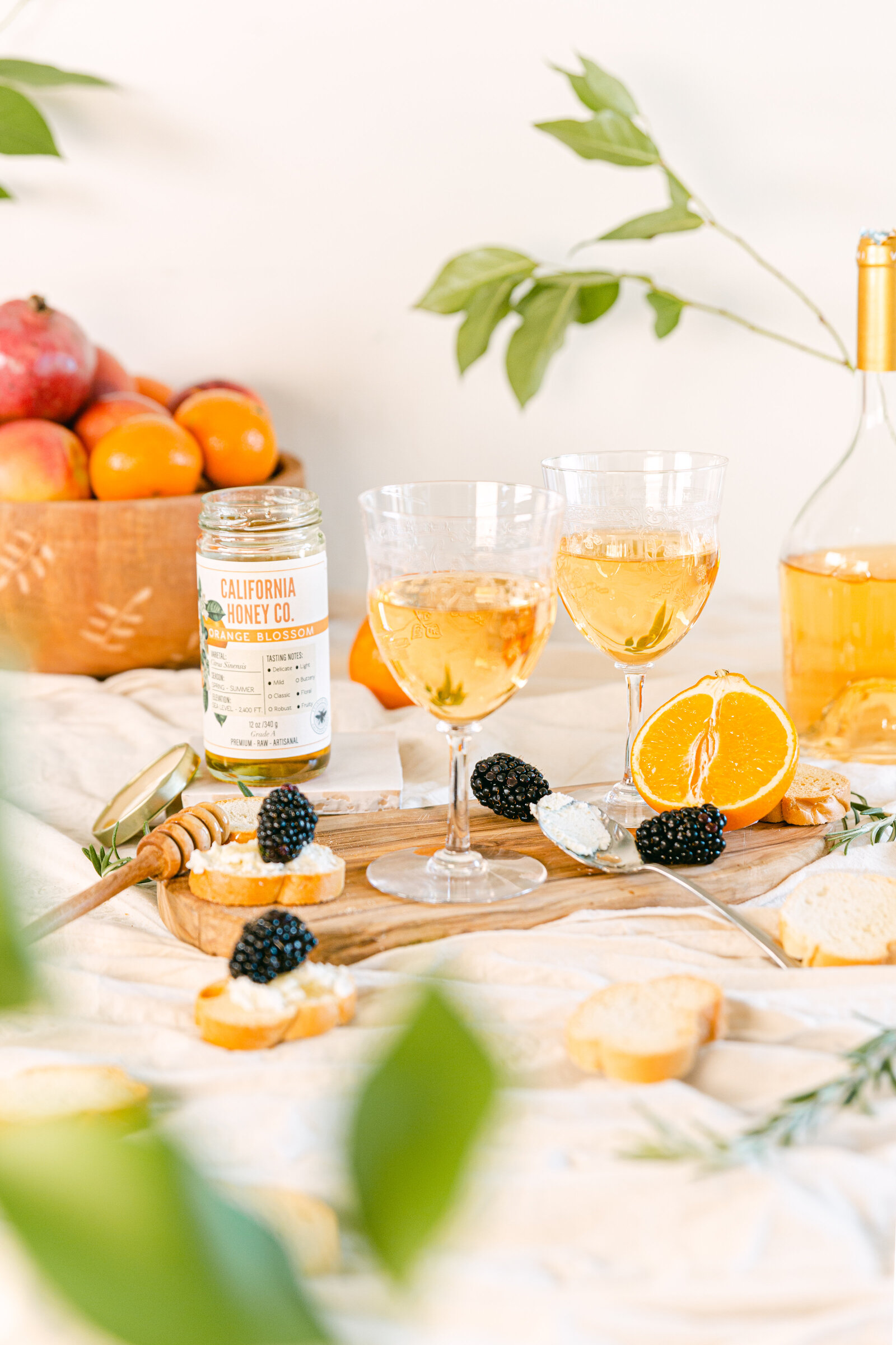 Outdoor lifestyle scene French vibes with crostinis and cheese paired with orange wine and honey for honey product photography in San Diego.