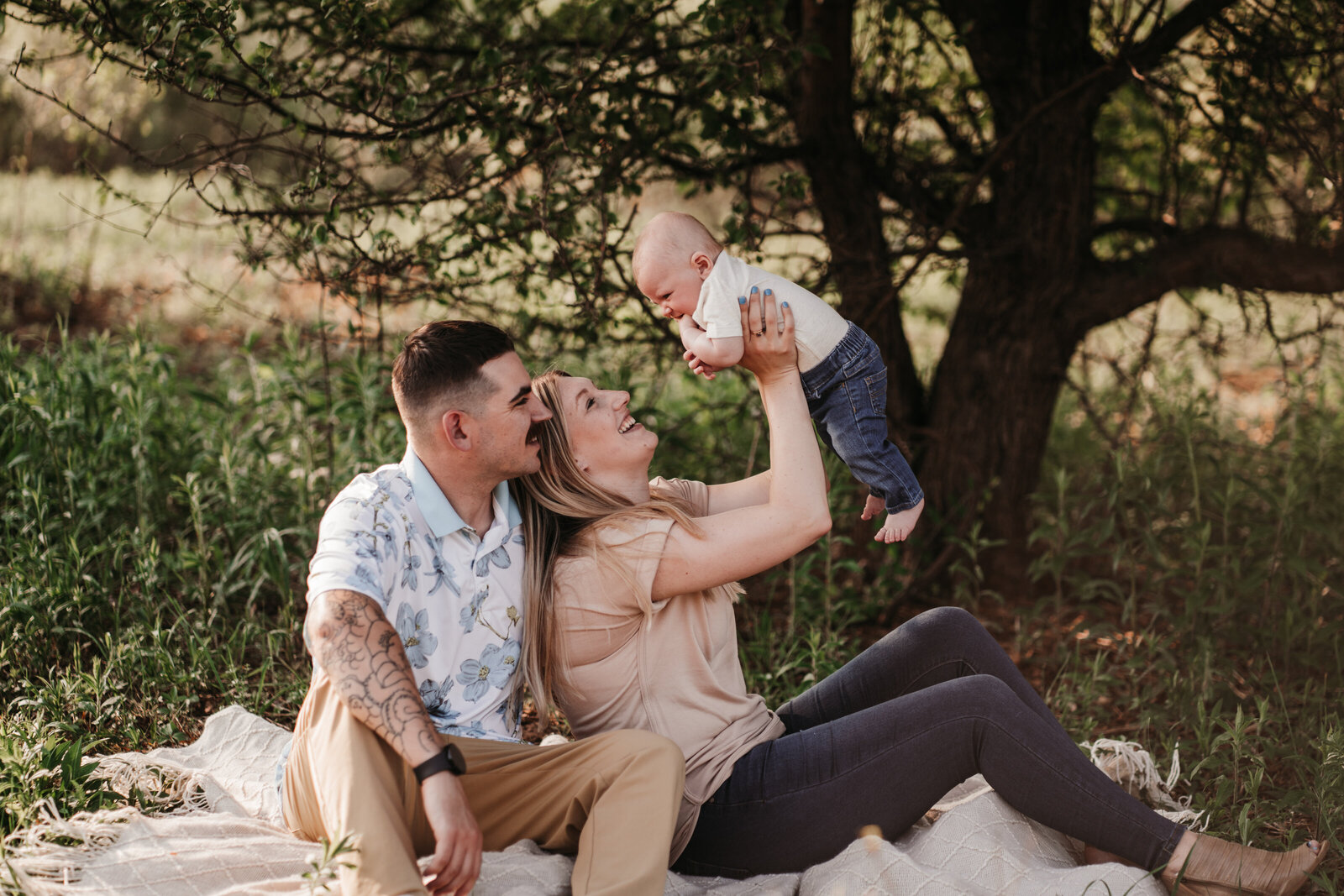 mom holding baby up in the air while dad looks on