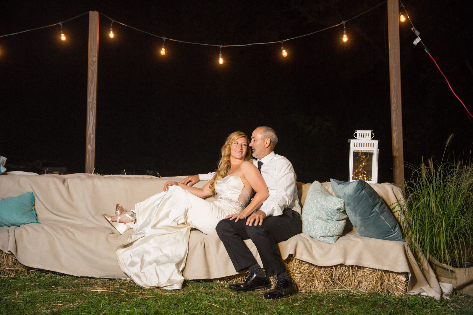 bride and groom sitting on the couch outside George Weir Barn at night