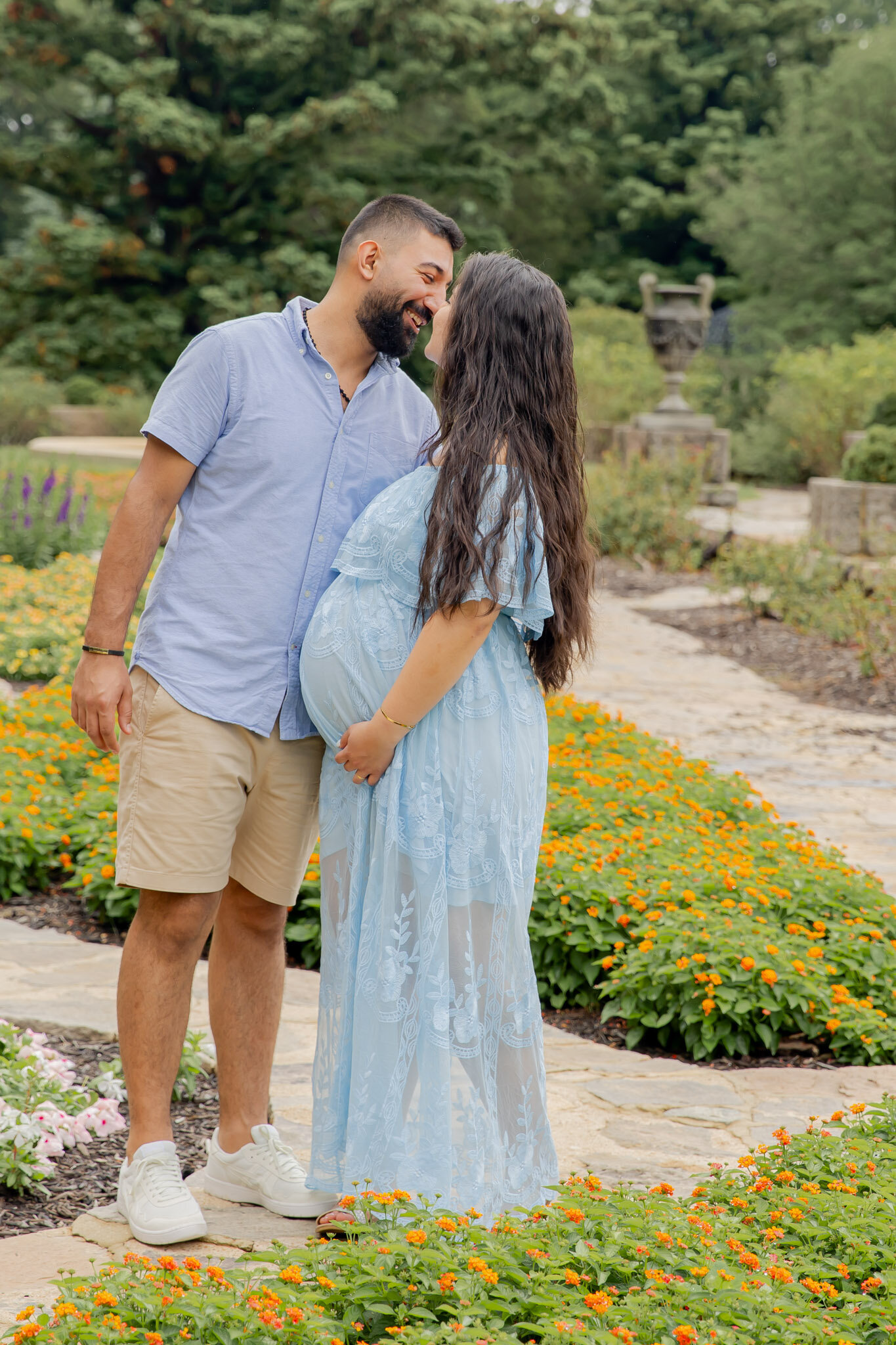 Mom and dad pose in a pretty garden in Richmond, VA, facing each other and almost kissing. Mom is holding her belly.