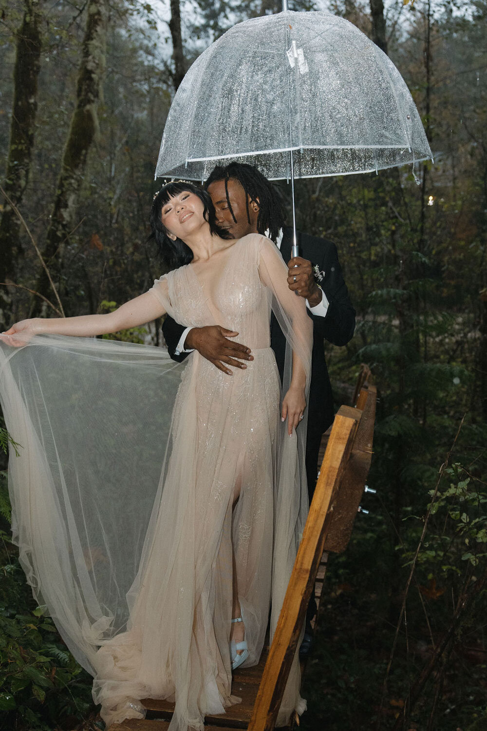Bride spinning her dress with the groom holding an umbrella