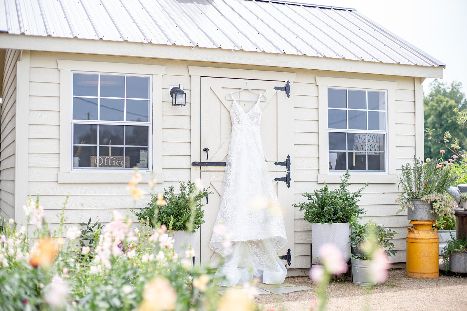 wedding dress hanging from cute white house with flowers