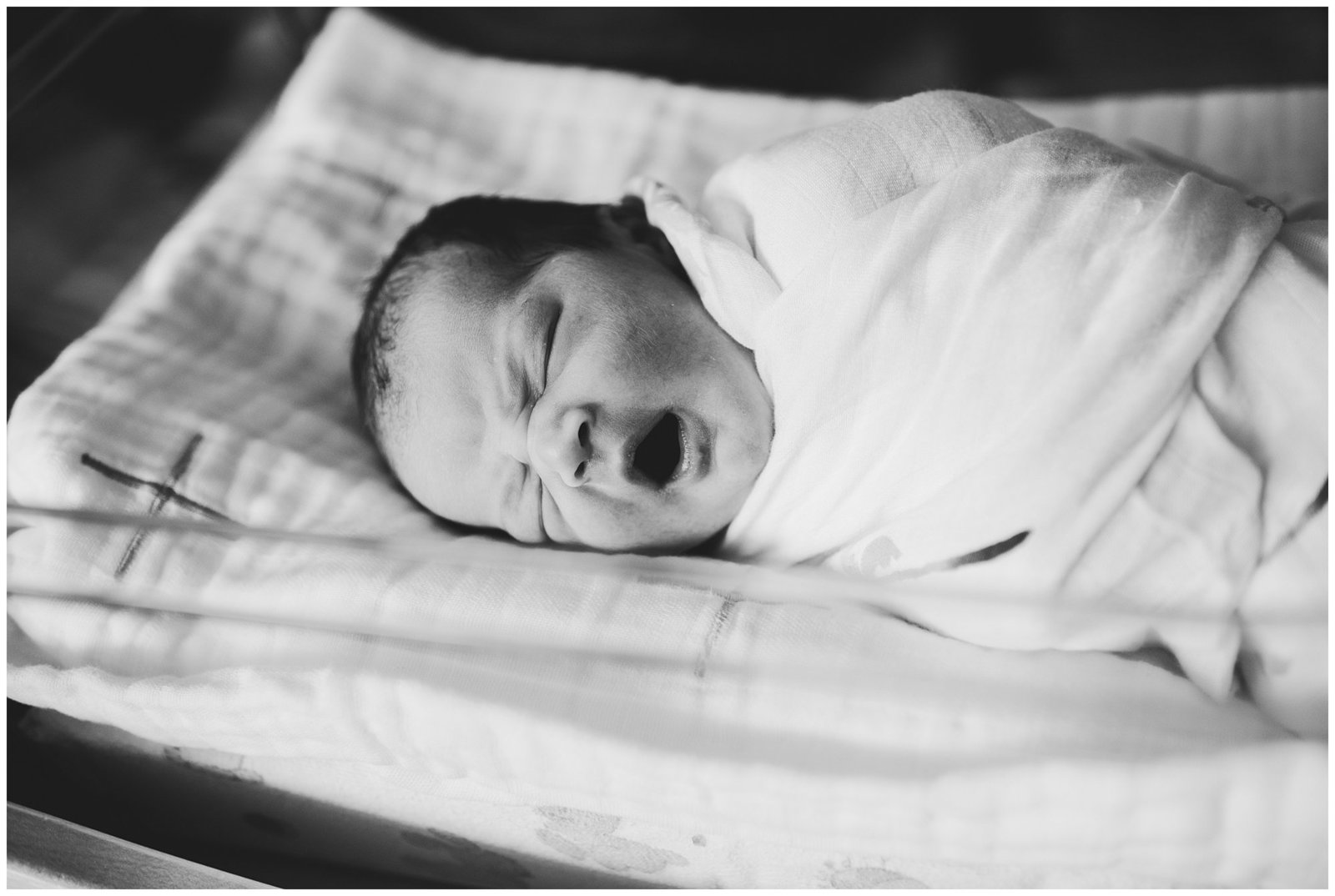 black and white photo of baby yawning in hospital bassinet seattle area photographer emily ann photography