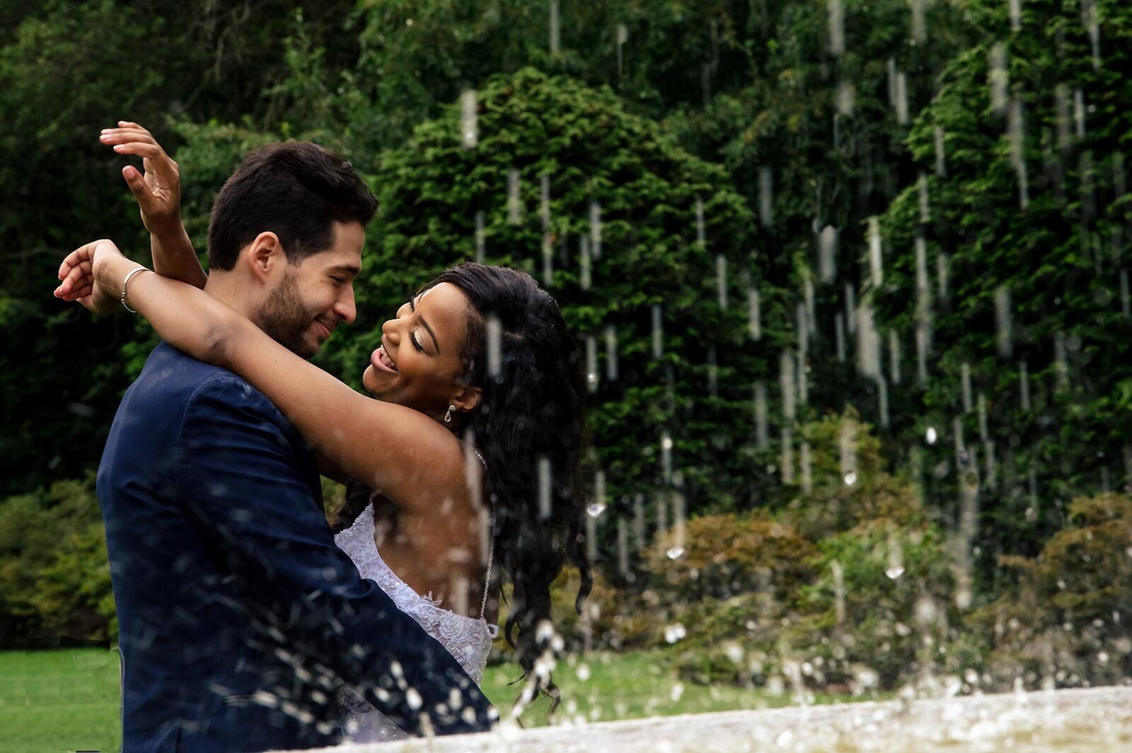 interacial couple-latino groom and his beautiful black bride in a very joyful candid embrace near the fountain in the Osborn Garden during their elopement ceremony in brooklyn's Botanical Garden