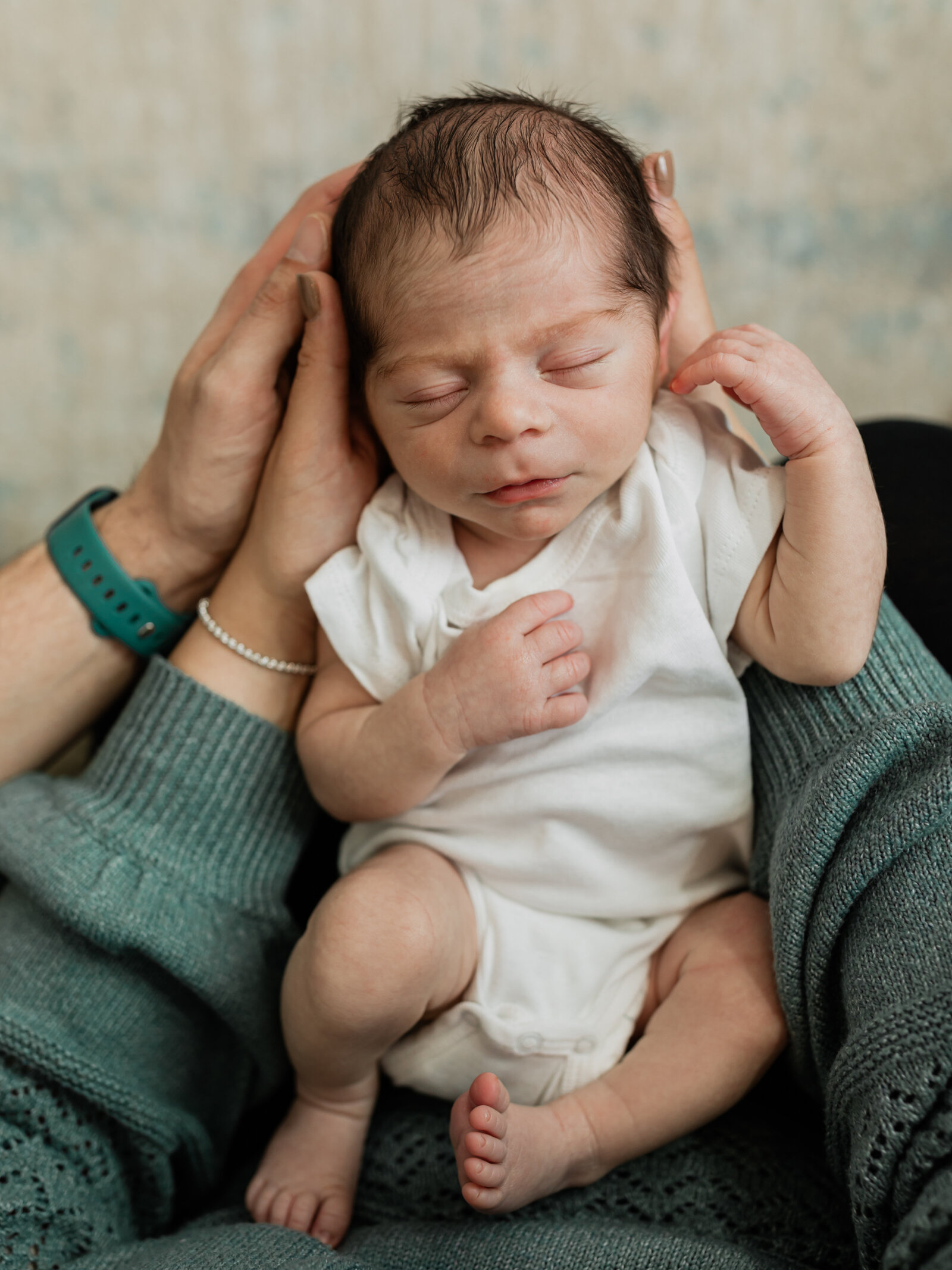 newborn baby boy in white onesie on moms lap for in home newborn session cleveland newborn photographer