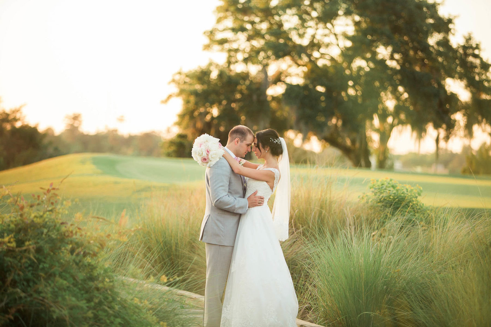 Bride and groom stand in a field at sunset, Daniel Island Club, Charleston, South Carolina
