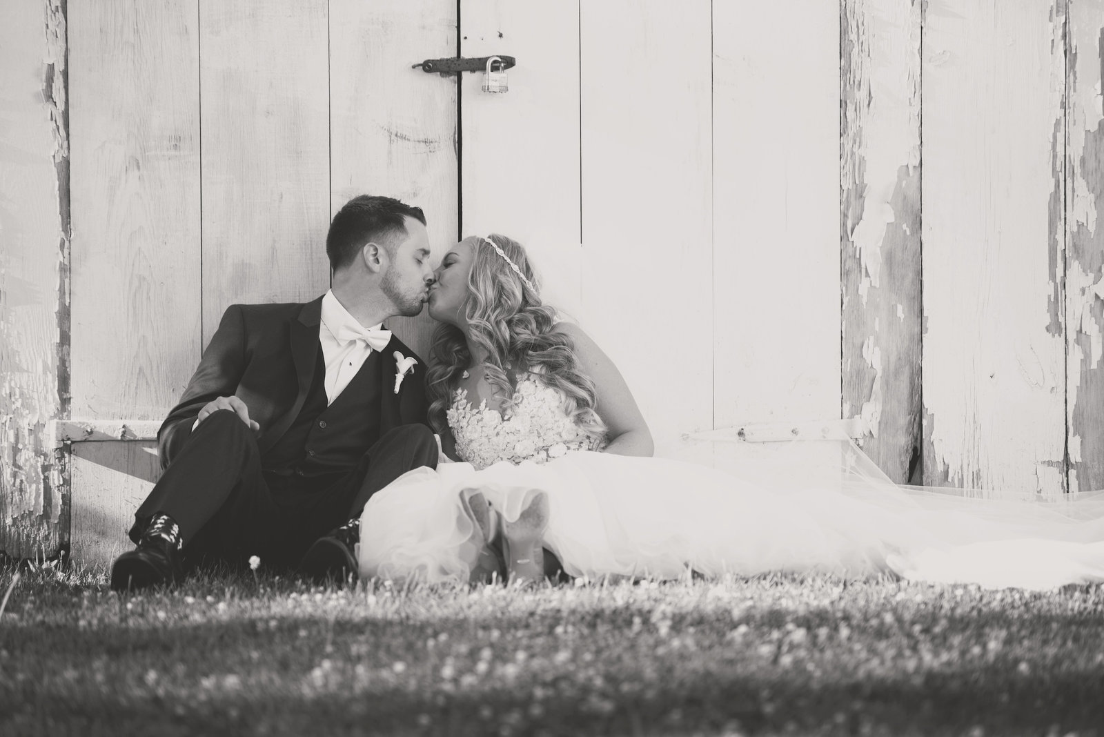 bride and groom kissing black and white photo against barn at The Barn at Old Bethpage