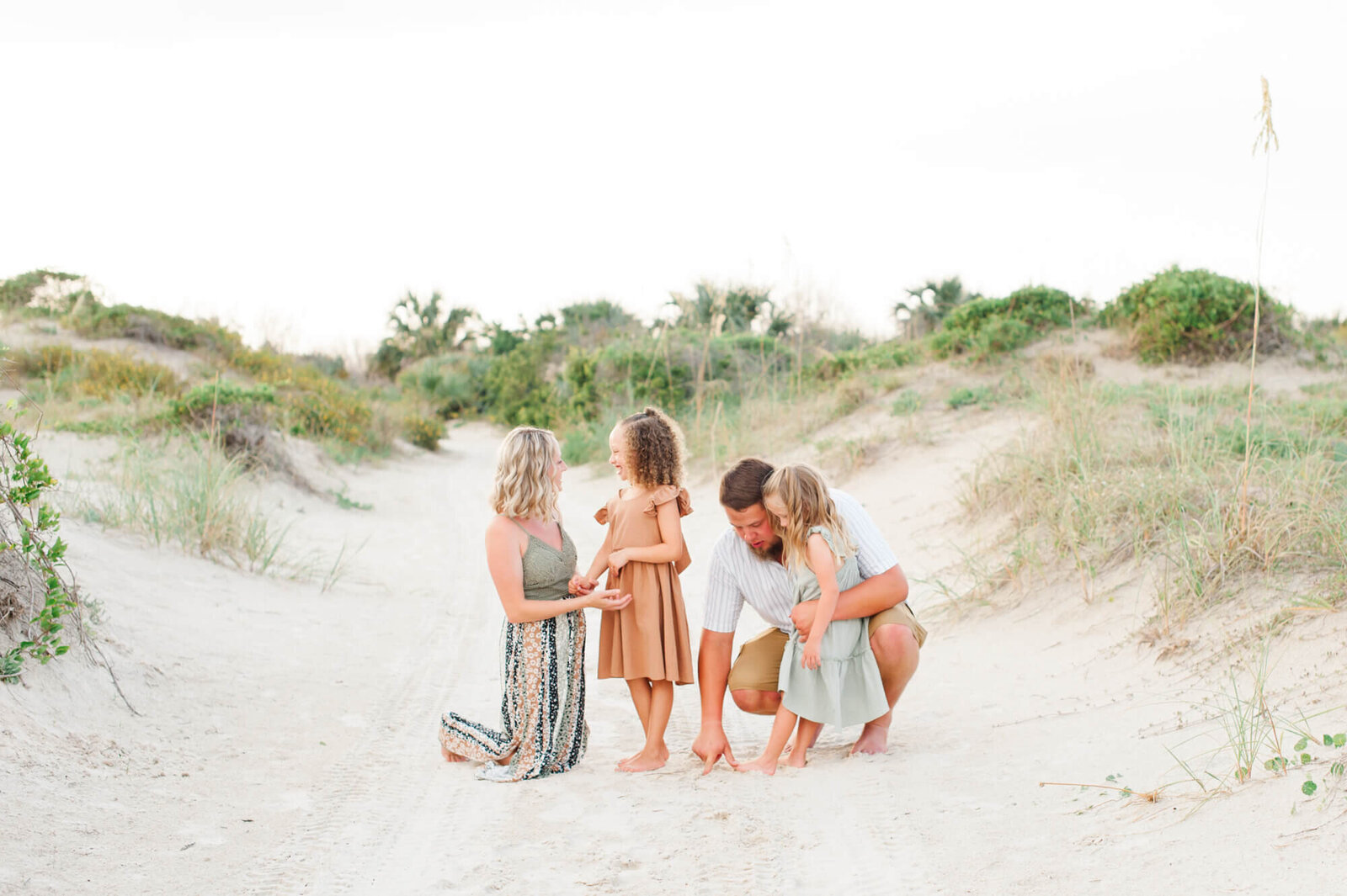 Family of four drawing in the sand during their Orlando family photoshoot
