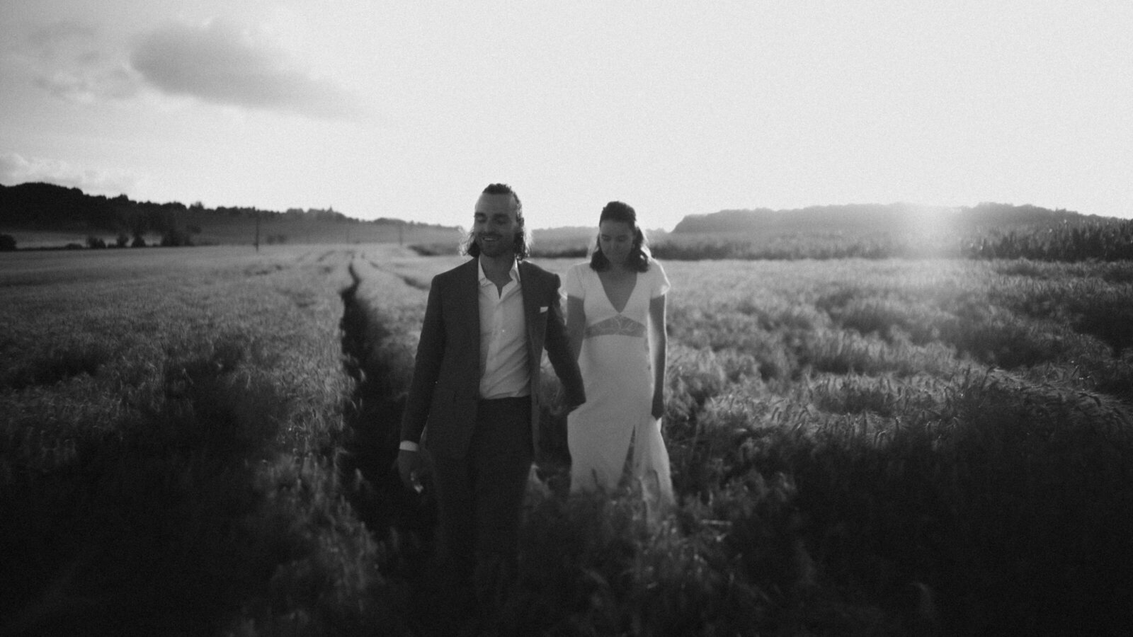 Bride and groom holding hands and walking in a wheat field. at golden hour