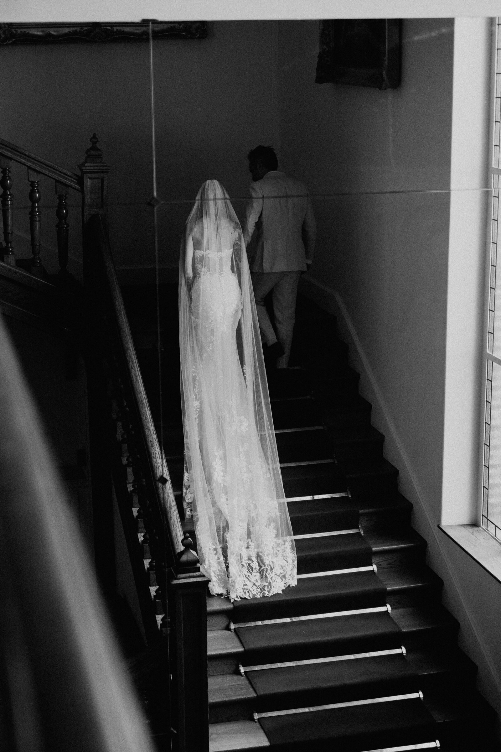 Mariés échangeant un baiser dans leur salle de repas décorée de chaises en bois, de lumières et de voilage blanc en attendant les invités. Photographie de mariage réalisée par Laura Termeau photographie.