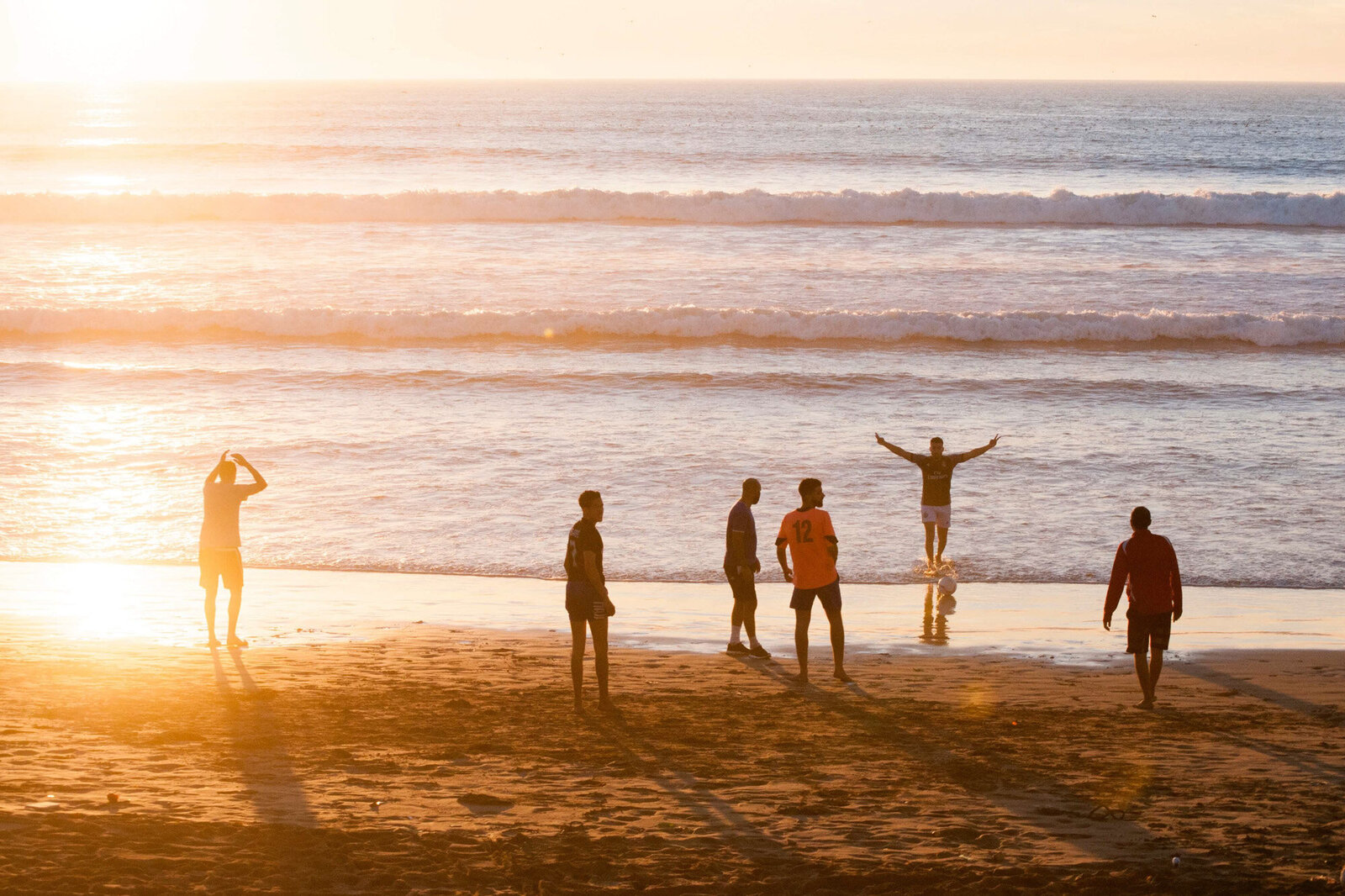 Group of friends having fun by the seashore while watching sunset