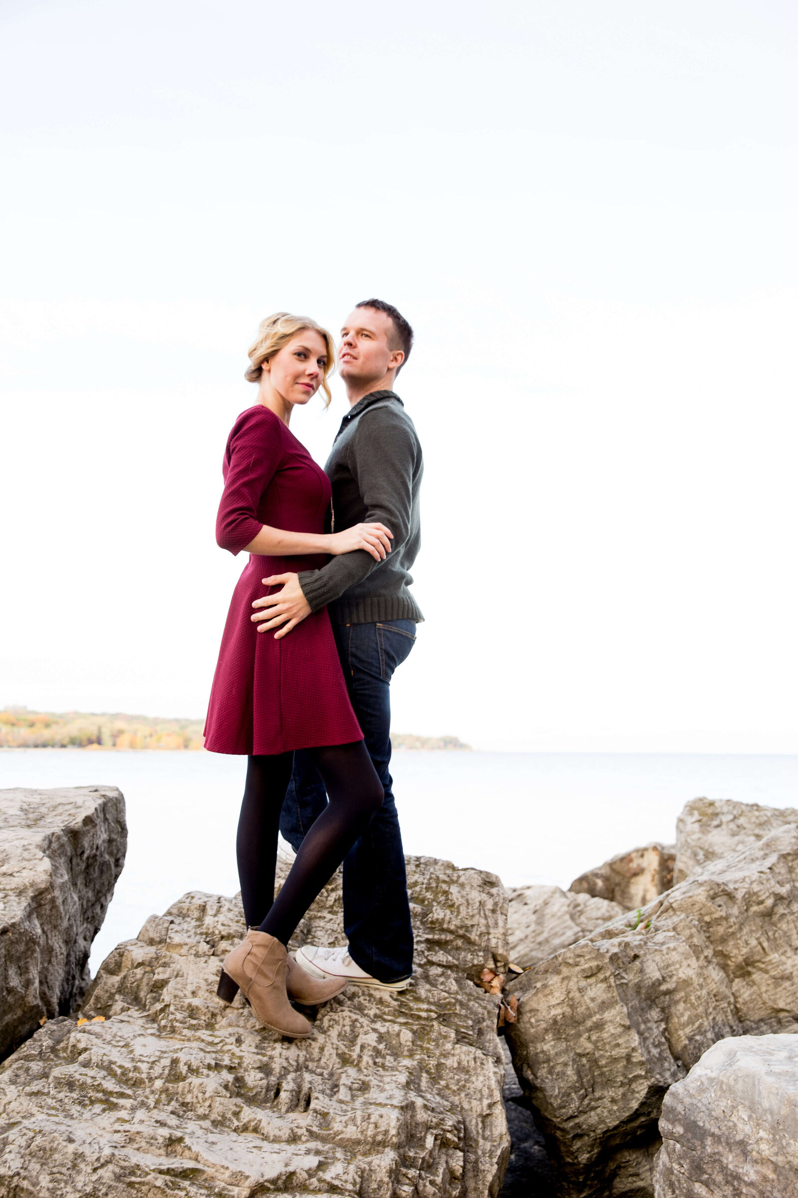 Couple on rocks at Toronto beach during engagement session in the fall.