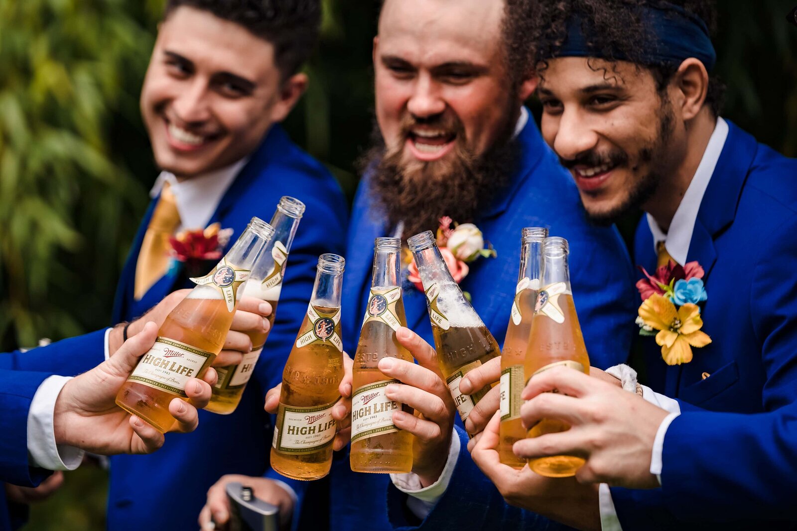 men in blue suits toast with Miller High Life beers on a wedding day