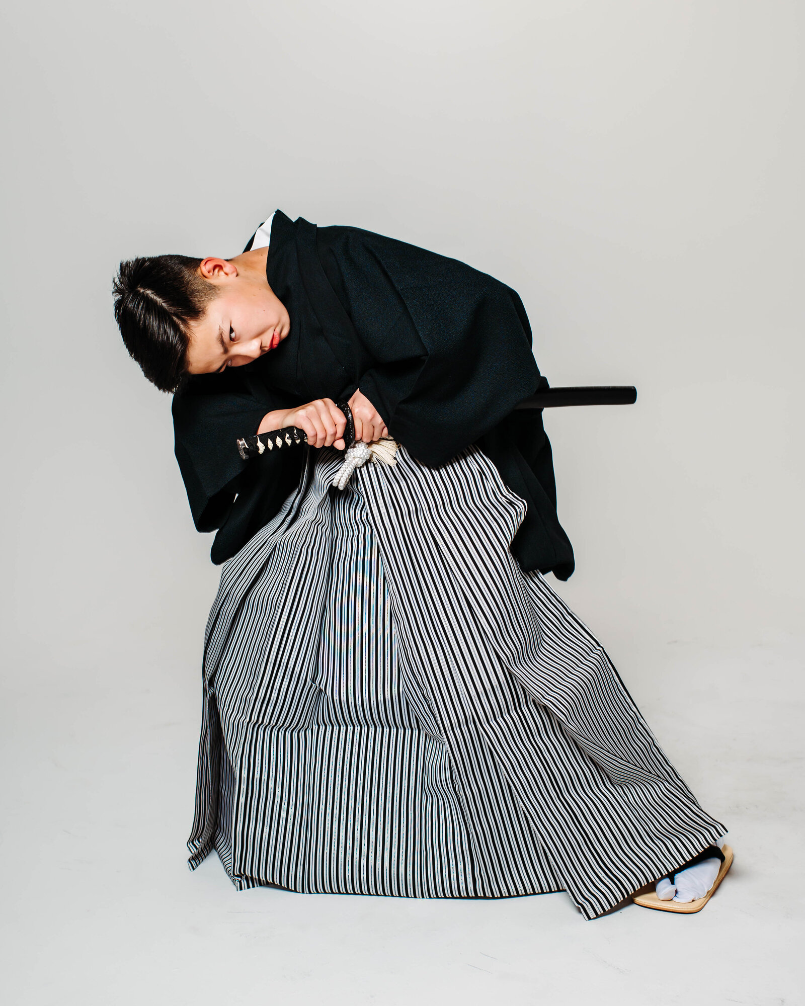 Boy in black montsuki hakama striking dramatic pose with katana for graduation | 卒業式 紋付袴 男の子 日本刀 ポーズ