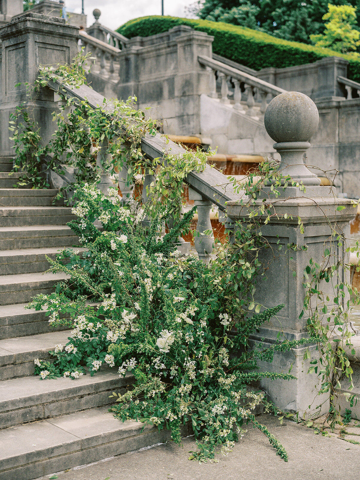 Elegant green and white wedding reception flowers going up stone steps to venue