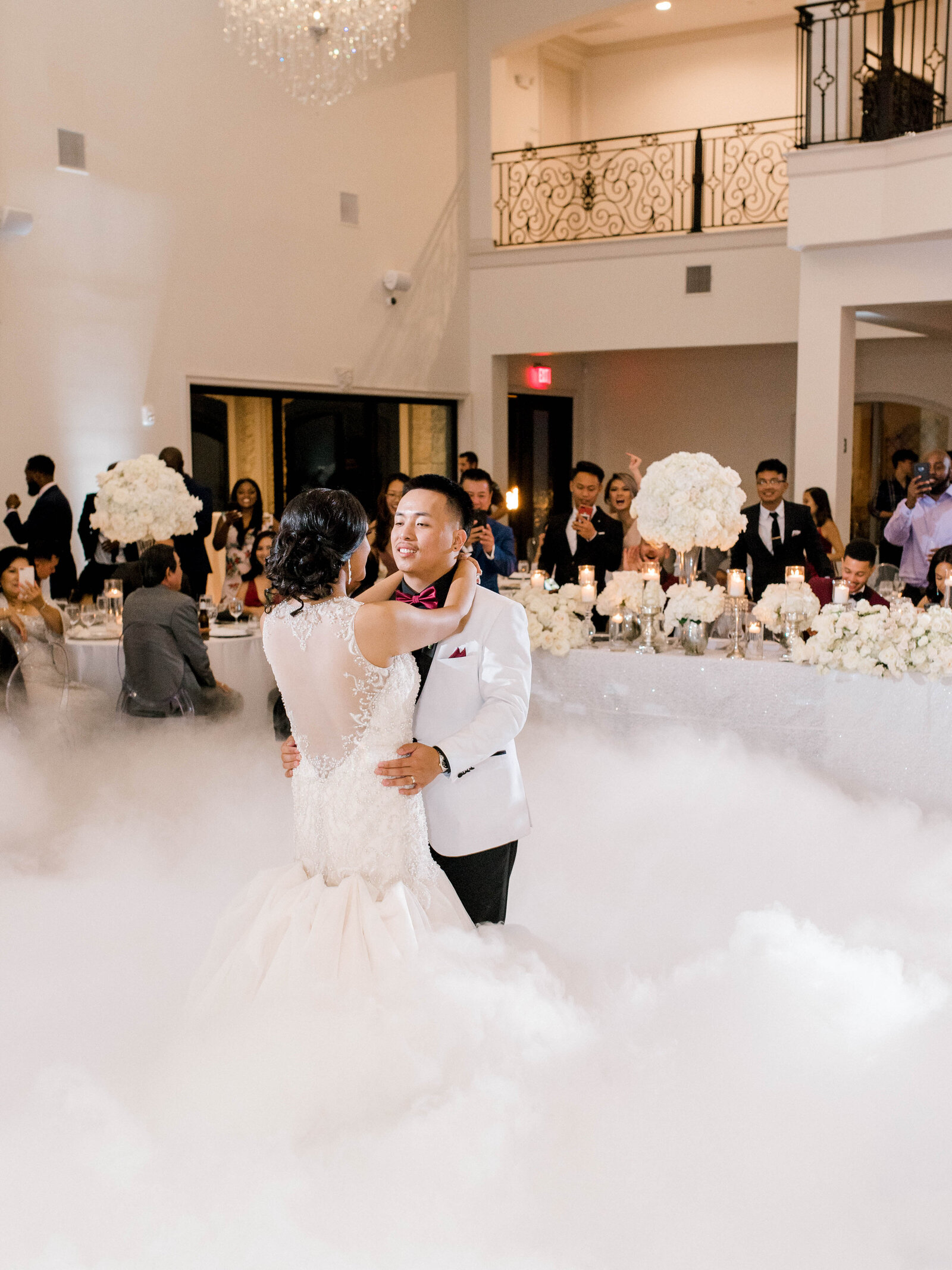 Bride and groom at their reception having their first dance in white fog