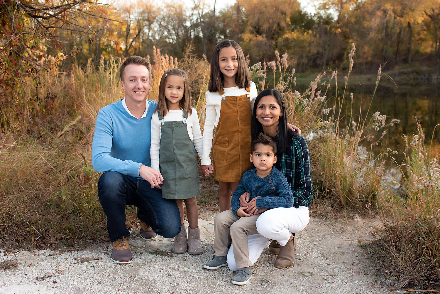 A family in front of tall grass at their fall family photo shoot.