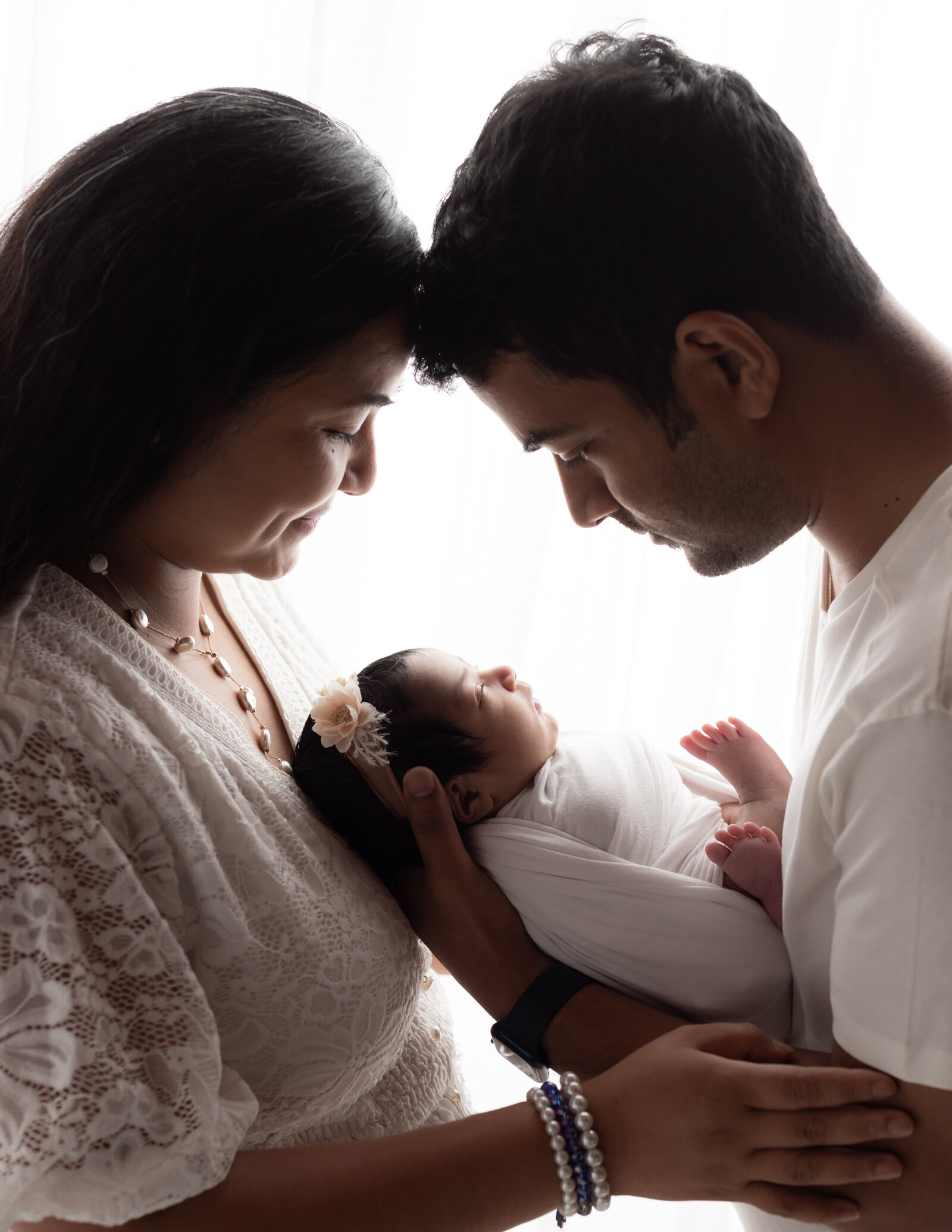 mom and dad holding newborn baby girl wrapped in white cleveland newborn photographer