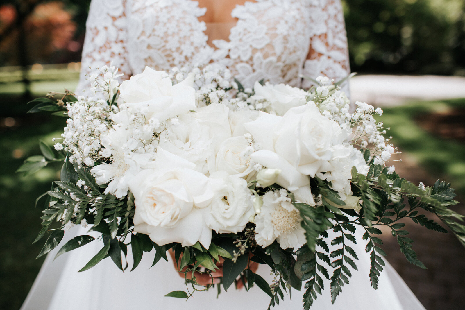 Bridal bouquet with white roses, white lisianthus, baby's breath, fern and ruscus.