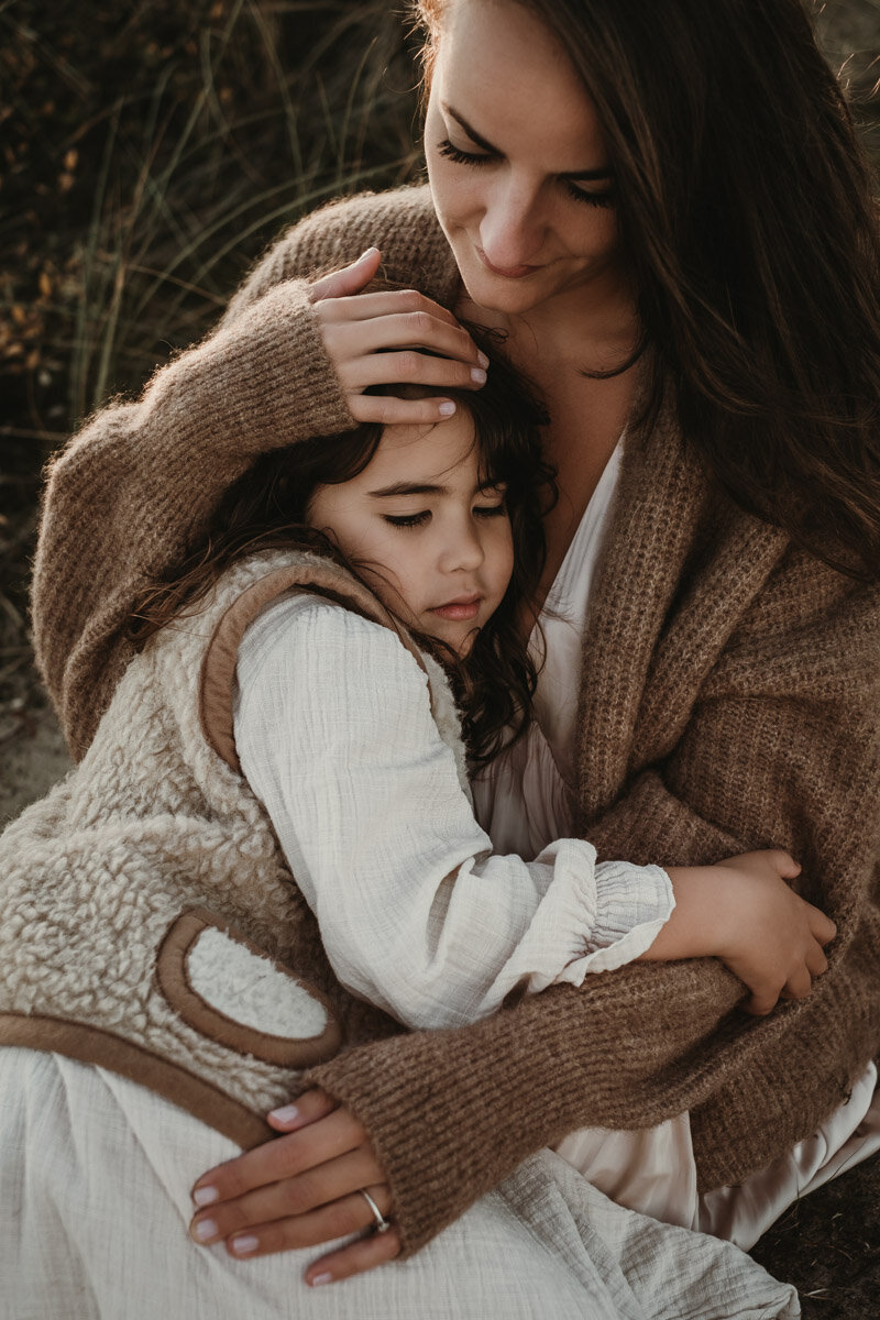 moeder en dochter knuffelend in de duinen