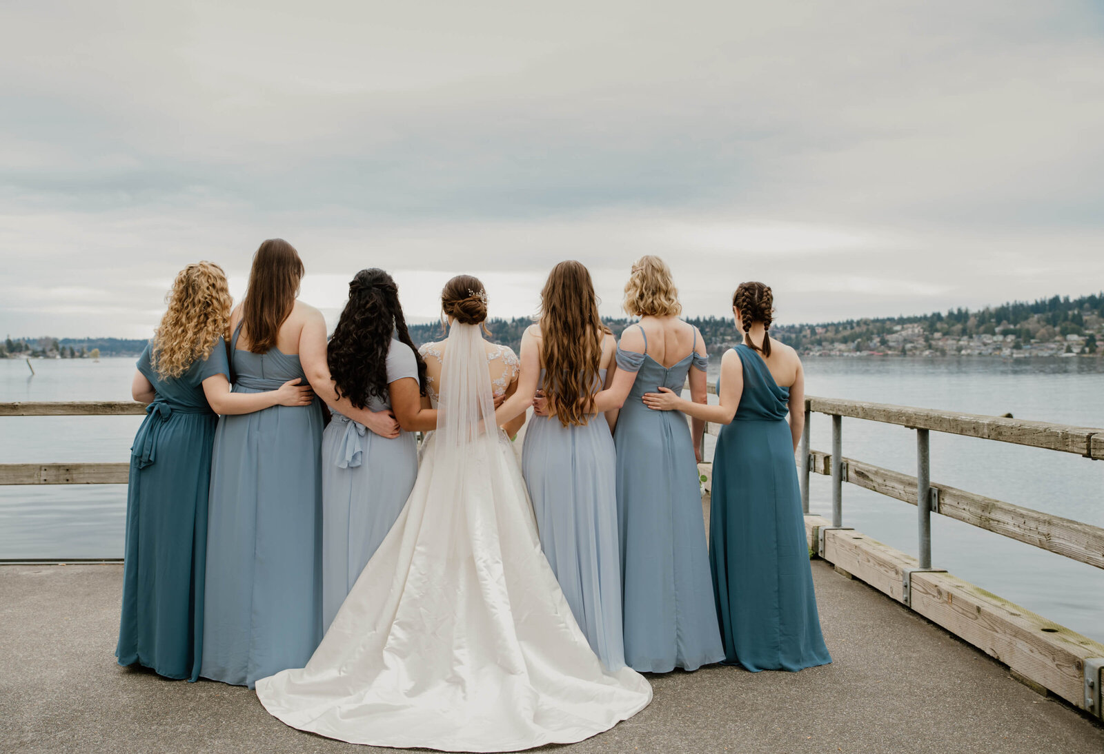 Bride and her bridesmaids show off back of dresses.