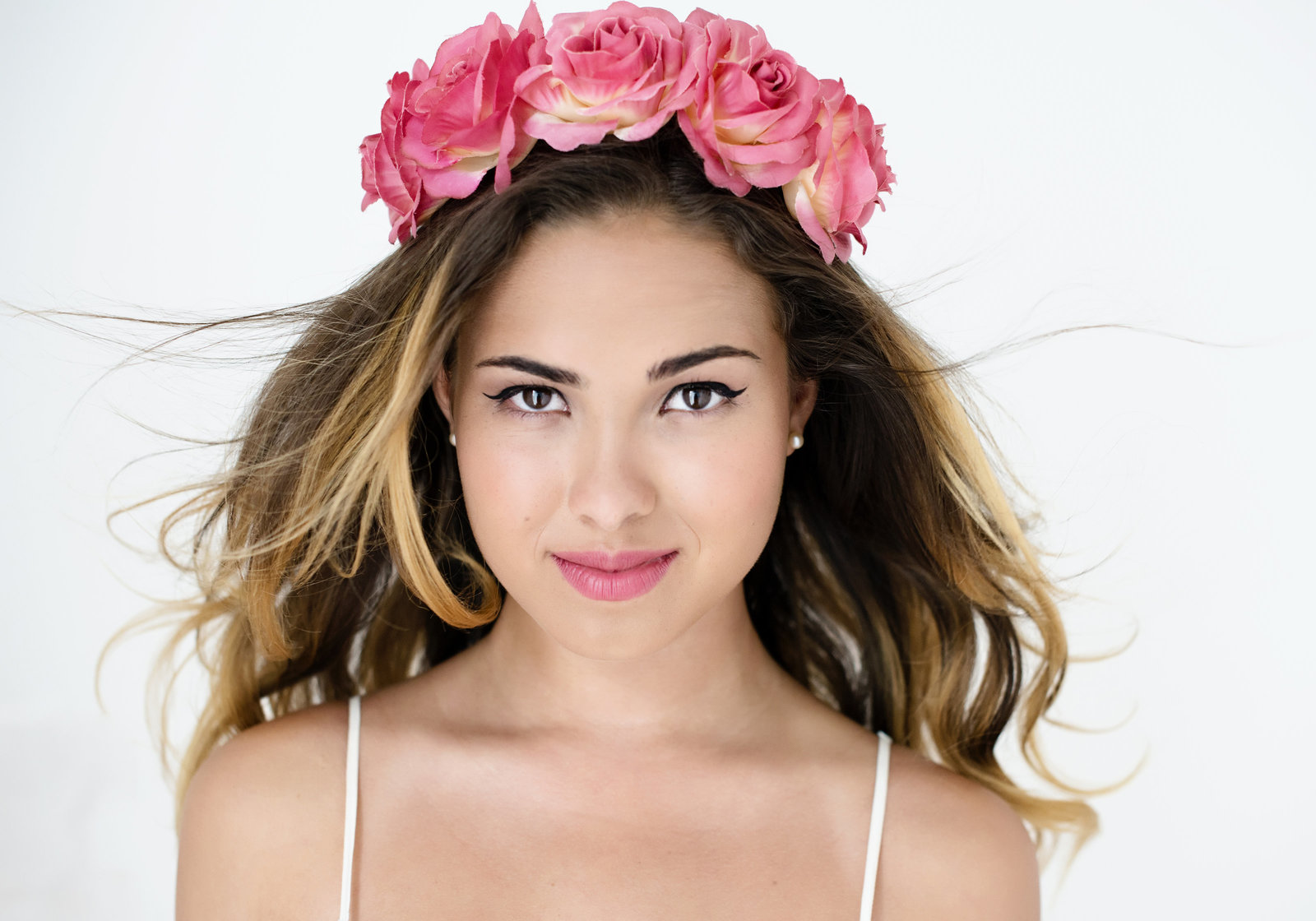 Toronto - branding Portrait  of young woman looking into camera with  flower  band on hair and eyes with eyeliner and  hair flowing in the air