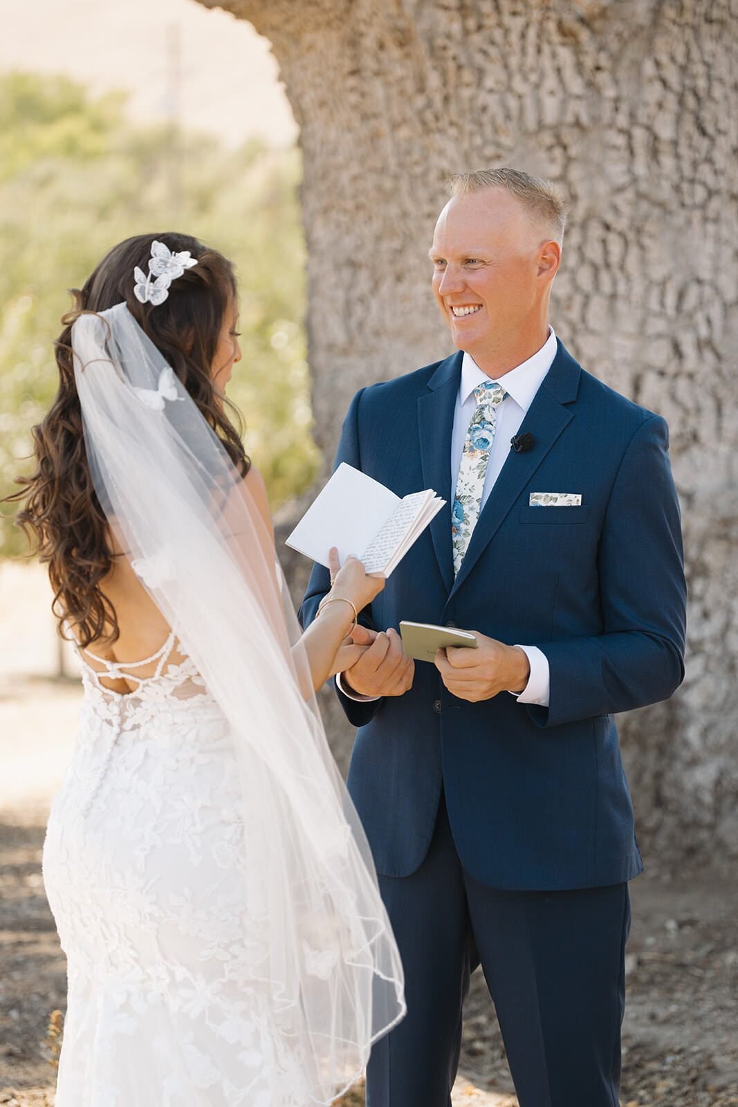 Bride and groom reading letters to each other under an oak tree